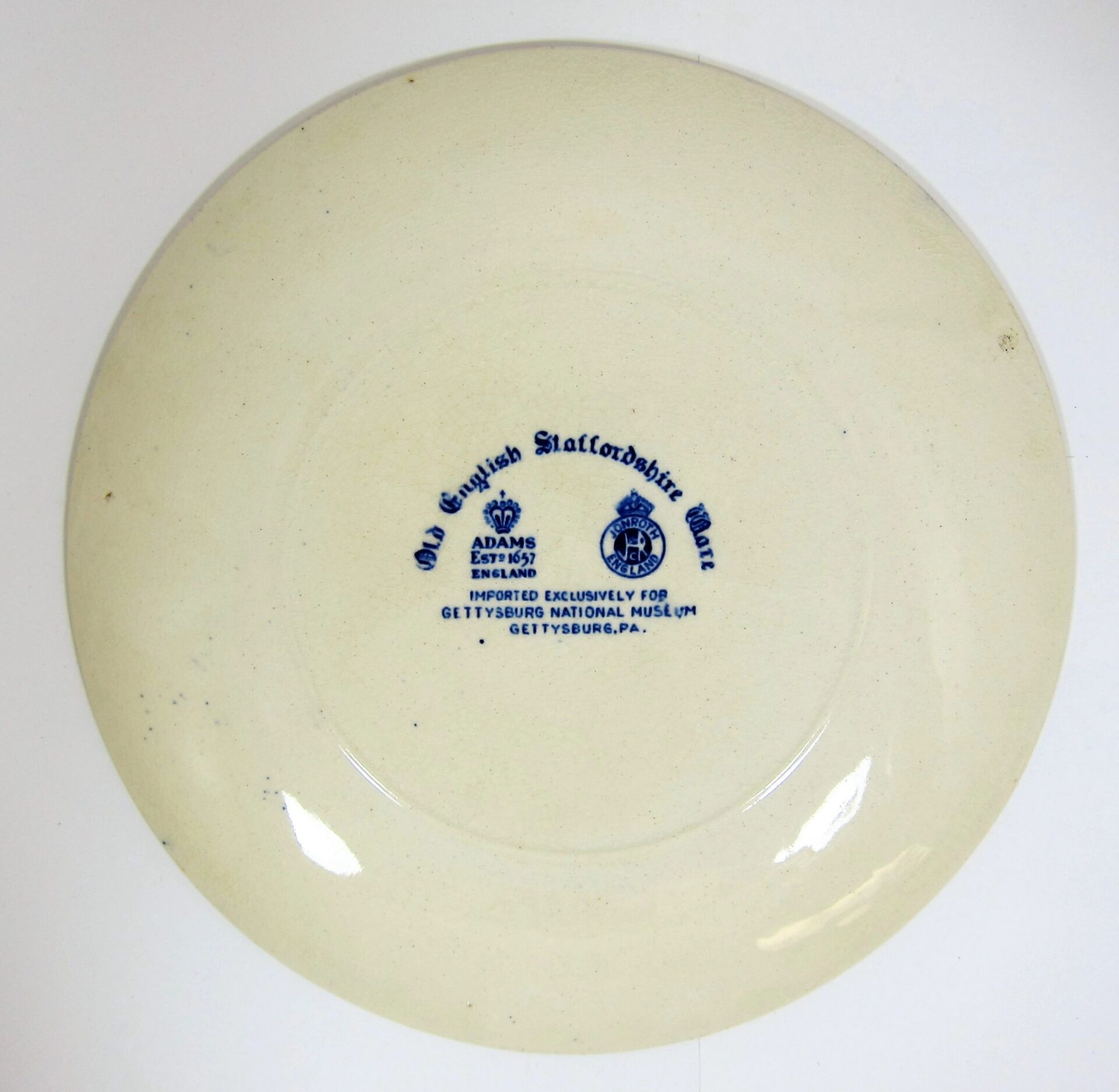 The underside of the Gettysburg Souvenir Plate Depicting Gettysburg National Museum features a blue "Old English Staffordshire Ware" stamp and notes it was imported for Gettysburg National Museum, Gettysburg, PA.