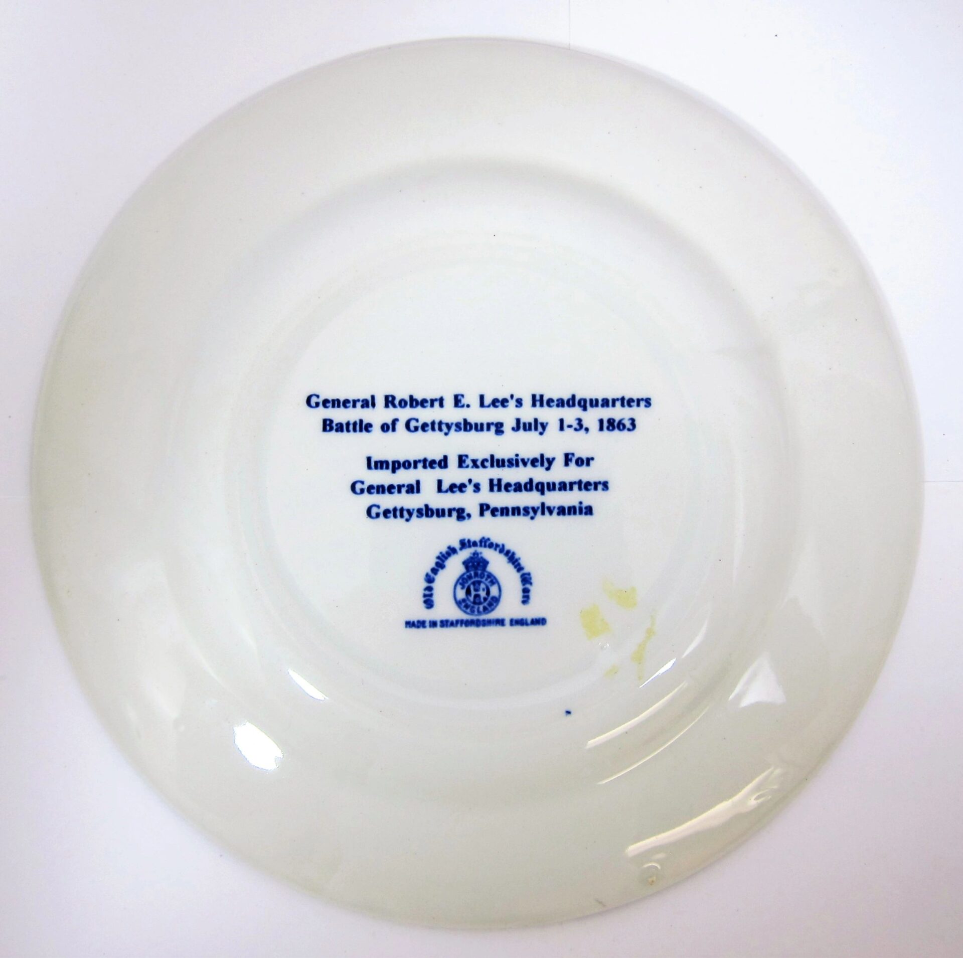 The back of the Gettysburg Souvenir Plate Depicting General Lee's Headquarters features blue text with "General Robert E. Lee's Headquarters, Battle of Gettysburg July 1-3, 1863" and manufacturer details, stamped on white ceramic.