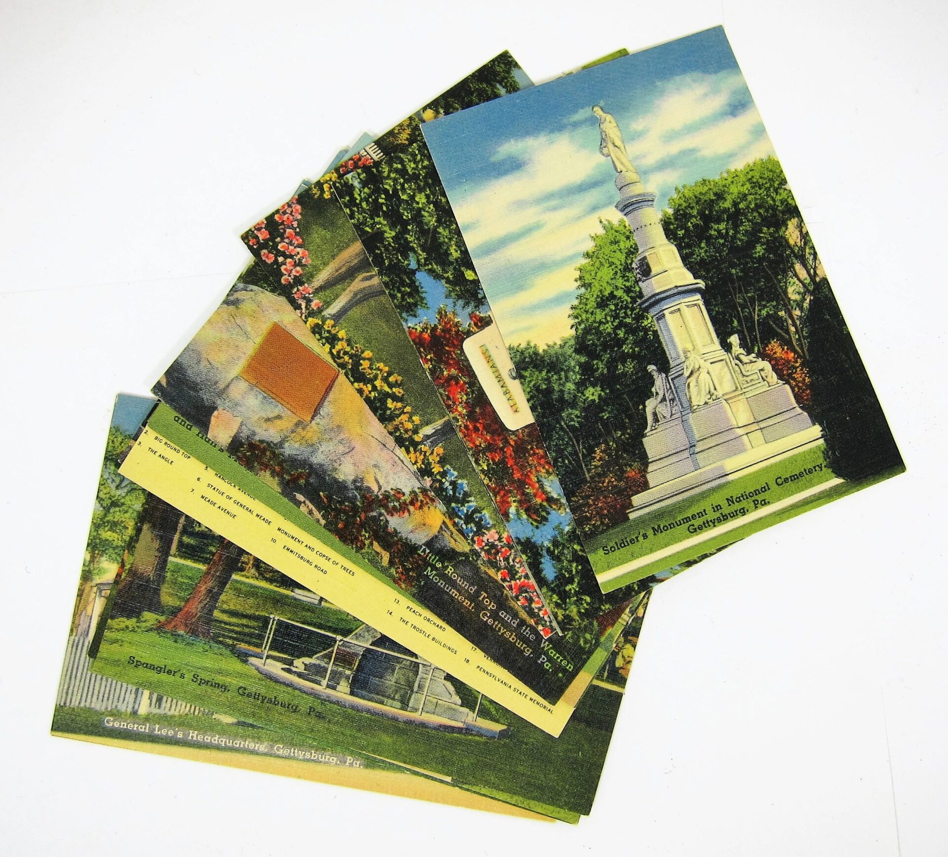 A stack of Gettysburg Souvenir Gettysburg Postcards featuring vintage illustrations of landmarks and monuments, including a statue on a stone pedestal in a park setting.