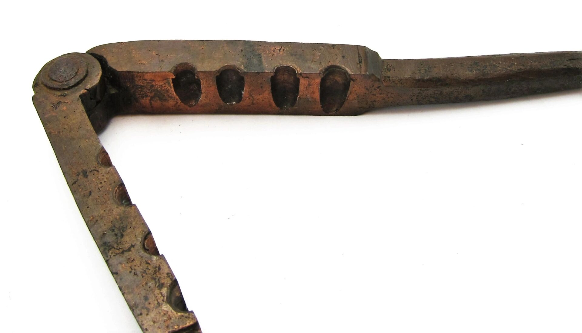 A Civil War era bullet gang mold, an antique metal tool with a hinge and grooved sections, rests on a white background.