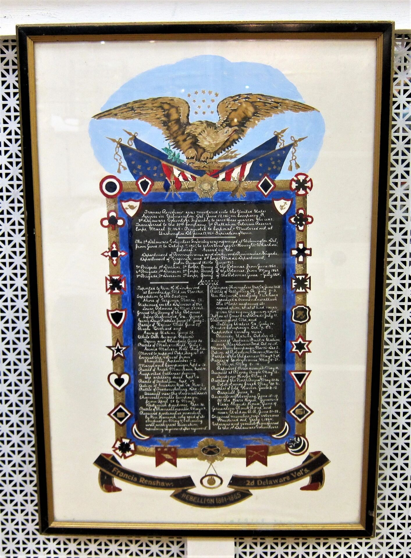 The Military Escutcheon of Francis Renshaw, 2nd Delaware Volunteer Infantry, features an eagle and U.S. flags at the top, medals around the border, and central text; displayed against a patterned background. / Sold.