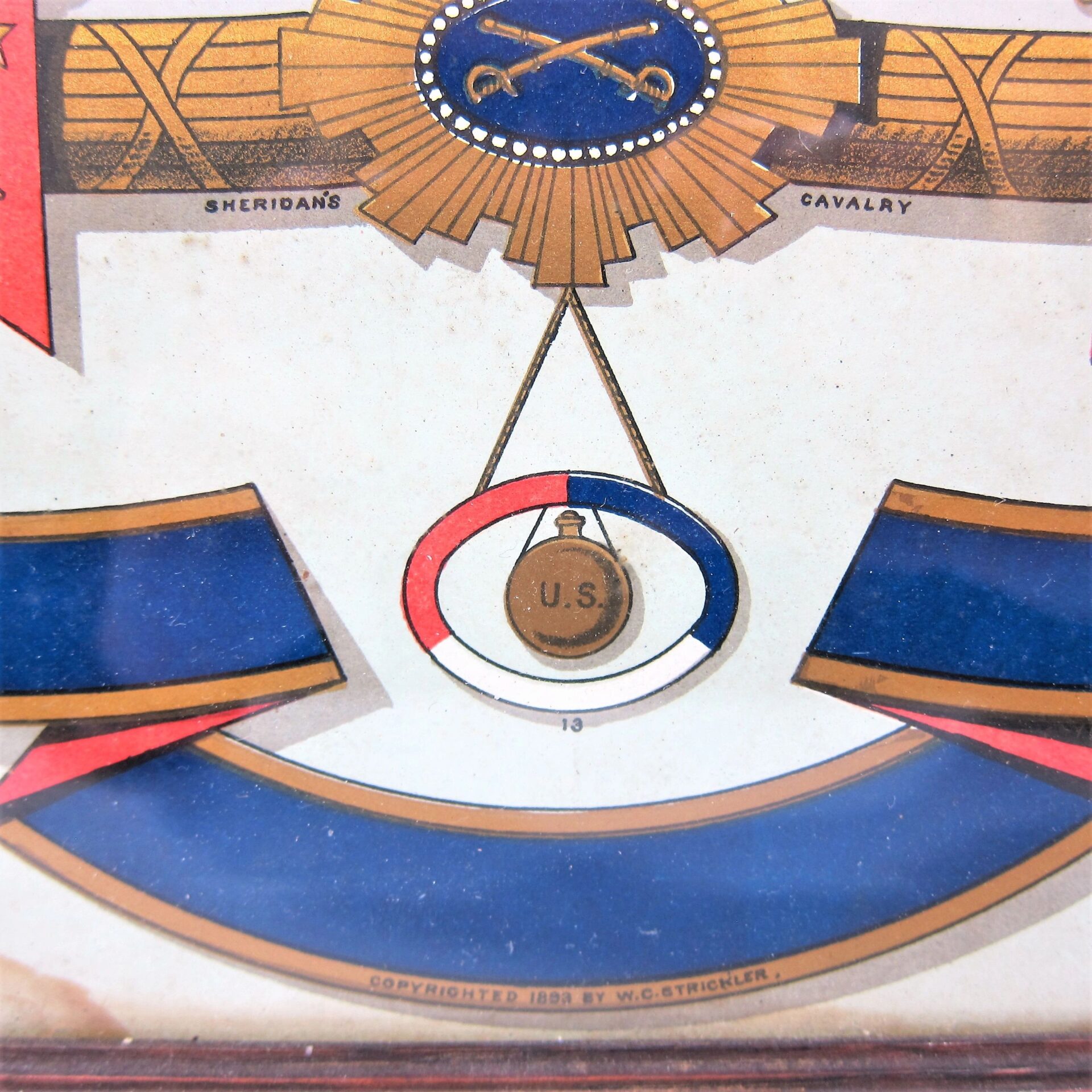 Close-up of the US Army Corp Escutcheon, featuring a decorative emblem with crossed swords labeled "Sheridan's Cavalry" and a central medallion marked "U.S." Copyright 1893 by W.C. Strickler.