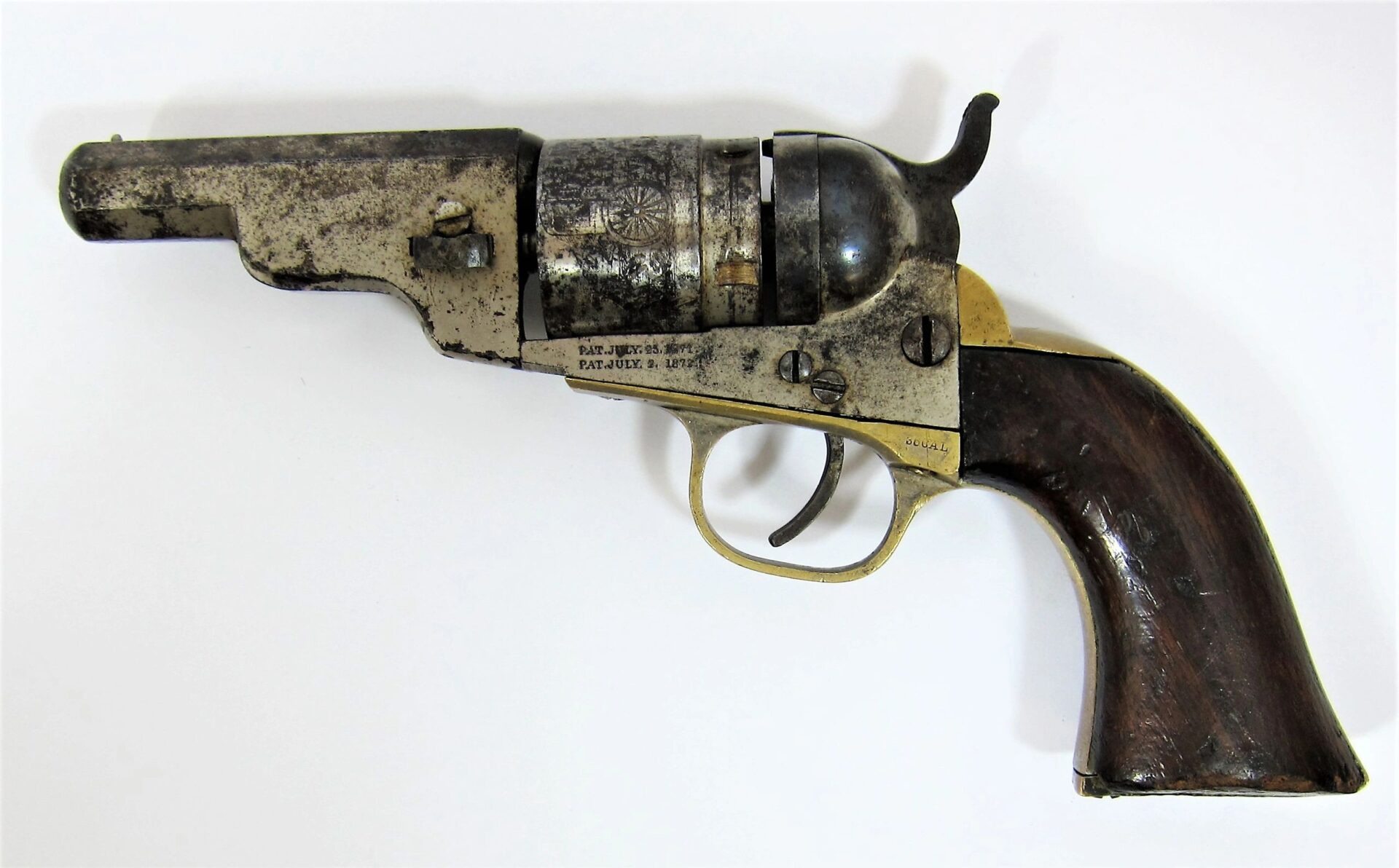 A Colt Wells Fargo Conversion revolver with a worn metal and wood finish and engraved cylinder is displayed on a white background.