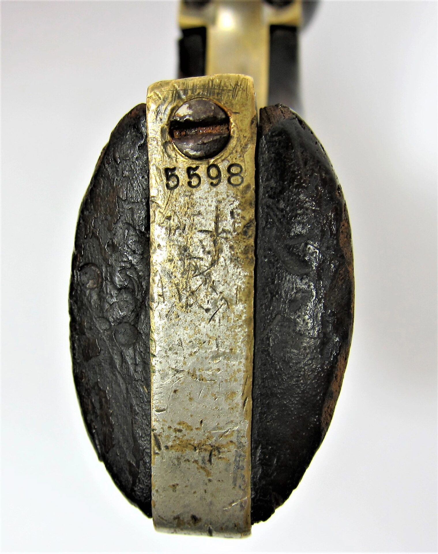 Close-up of the bottom of a Colt Wells Fargo Conversion grip, featuring a brass plate engraved with the number 5598 next to a screw.