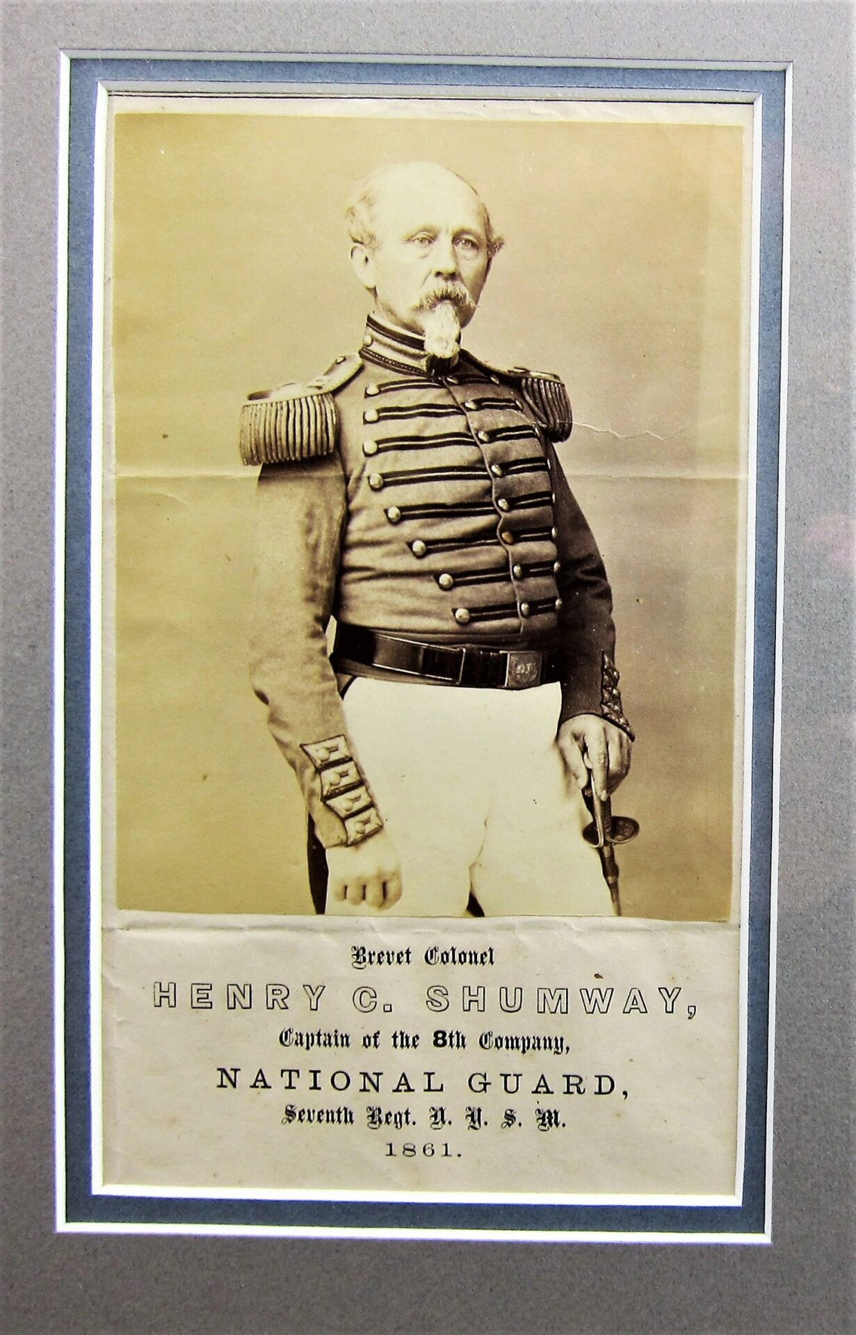 Albumen portrait of Brevet Colonel Henry C. Shumway, Captain of the 8th Company, 7th Regiment NYSM, in uniform with epaulets and sword.