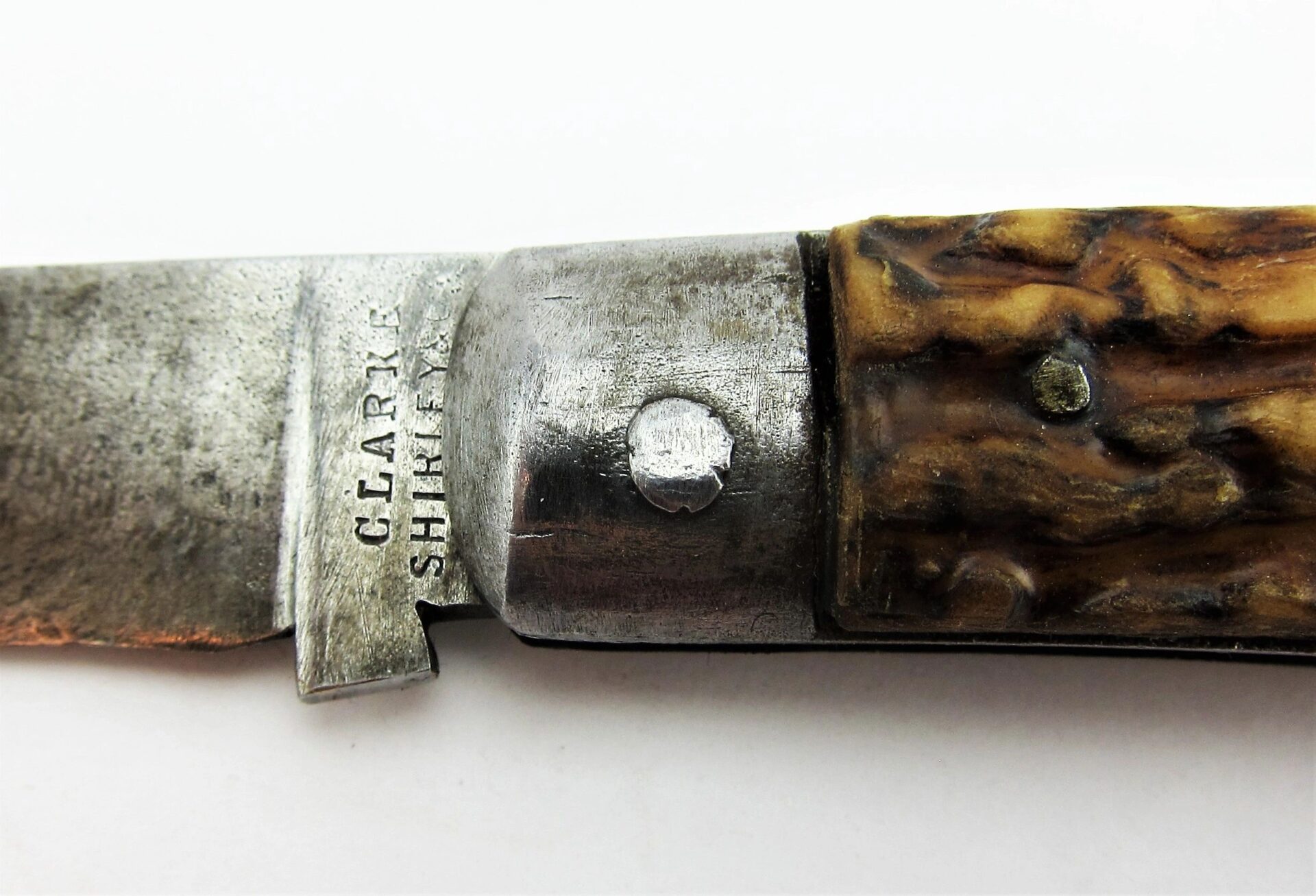 Close-up of a Rare Civil War Era Navy Sailor's Working Pocket Knife with a textured handle and "CLARK SHEFFIELD" stamped on the metal near the blade.