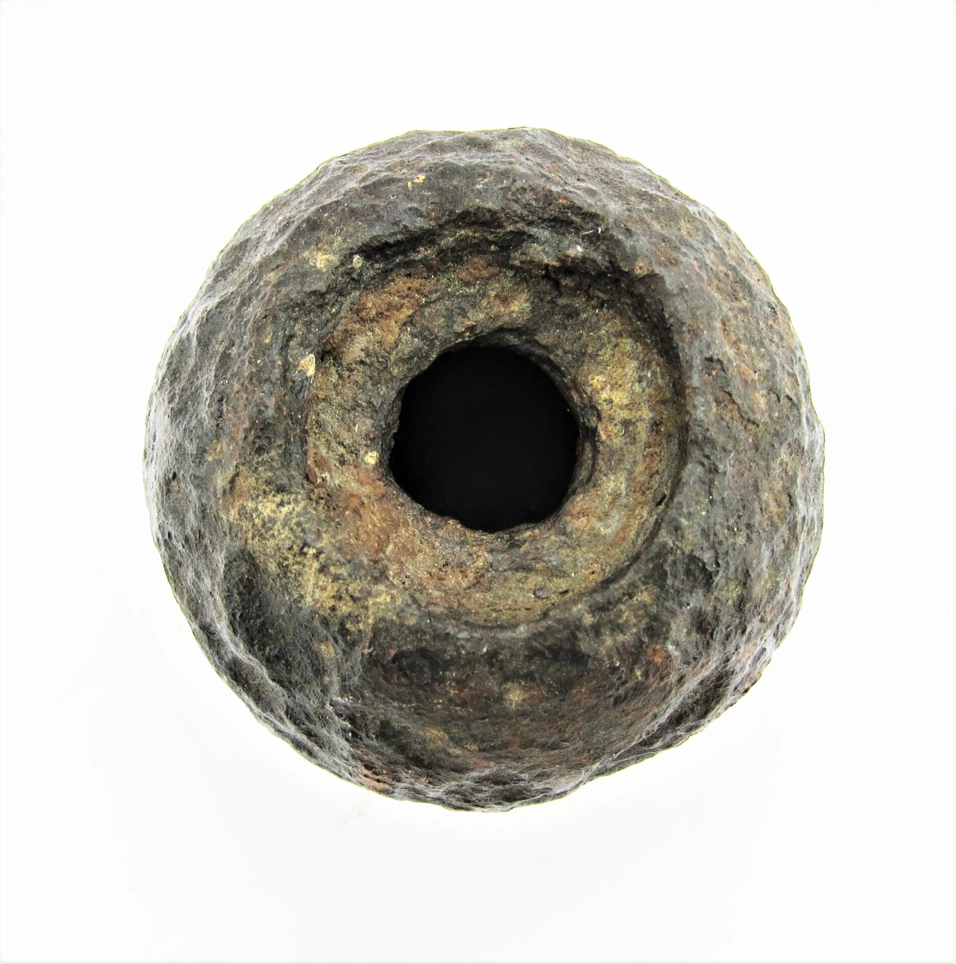 A 6 Pound Bormann Artillery Shell, round and weathered with a large central hole, is displayed against a white background.
