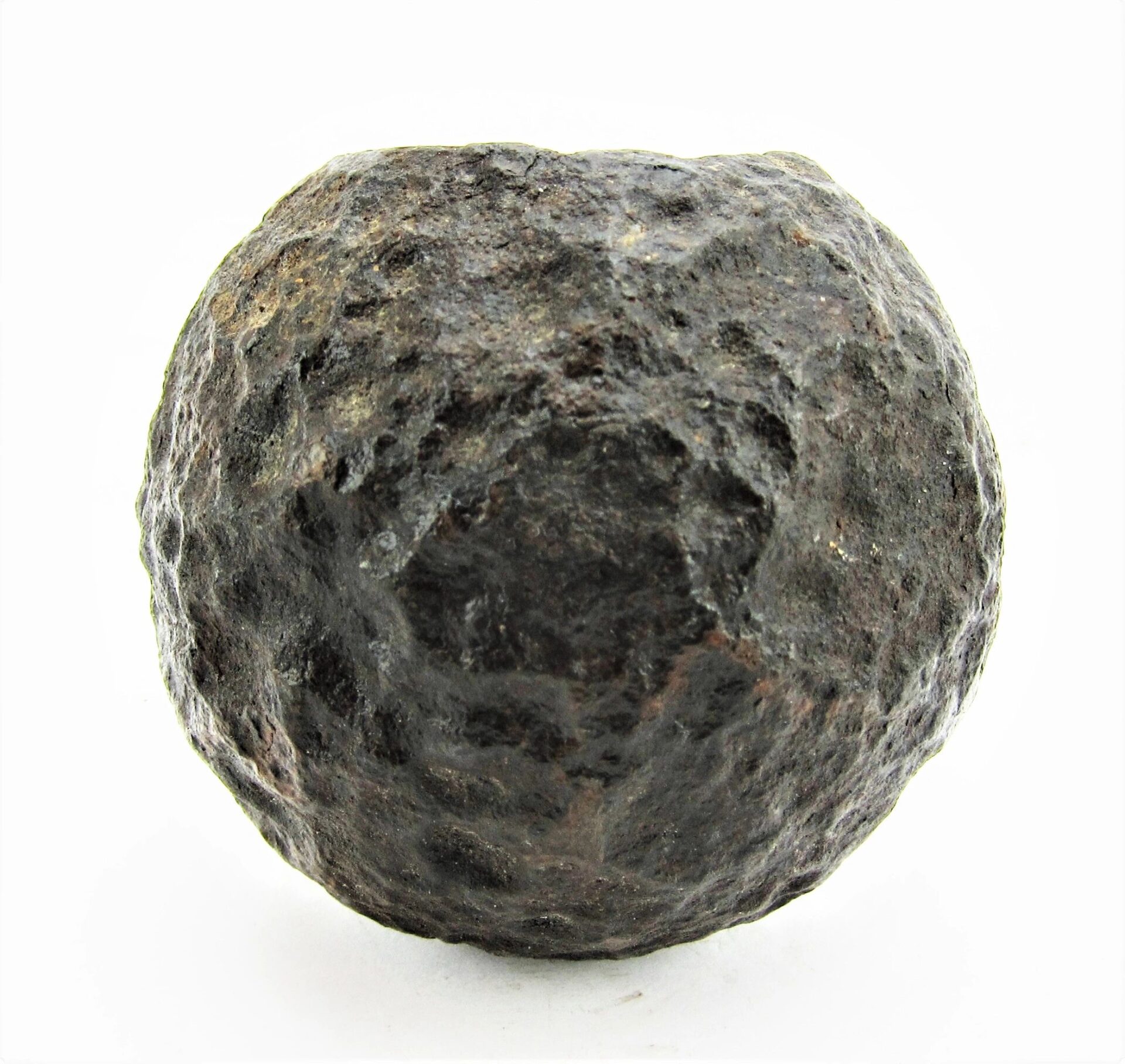 A rough, dark, spherical 6 Pound Bormann Artillery Shell with a pitted surface is displayed against a plain white background.