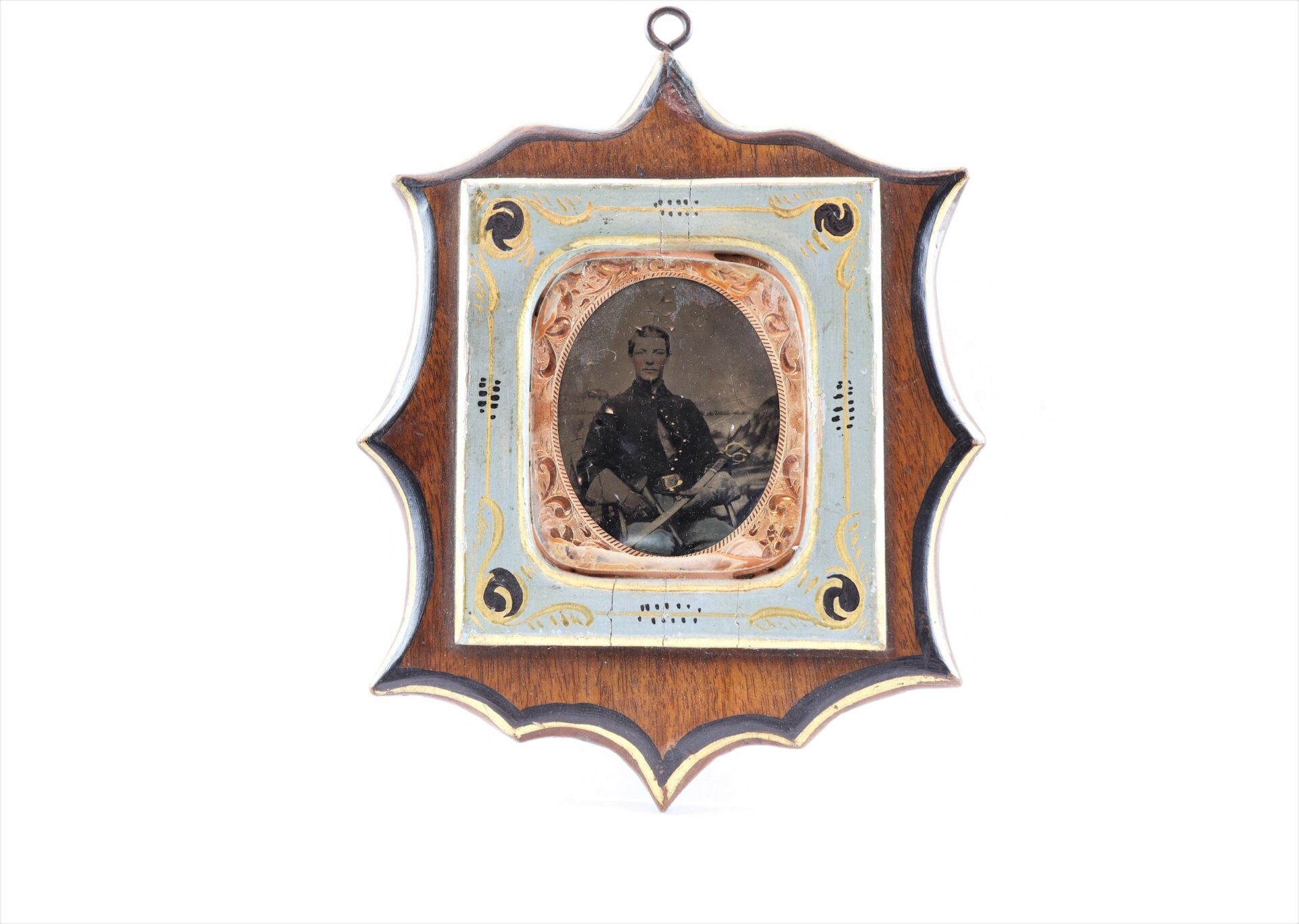 The Cavlary Image is a framed antique photograph showing a person in formal attire, set in a decorative wooden, painted frame with scalloped edges and a small hanging loop.