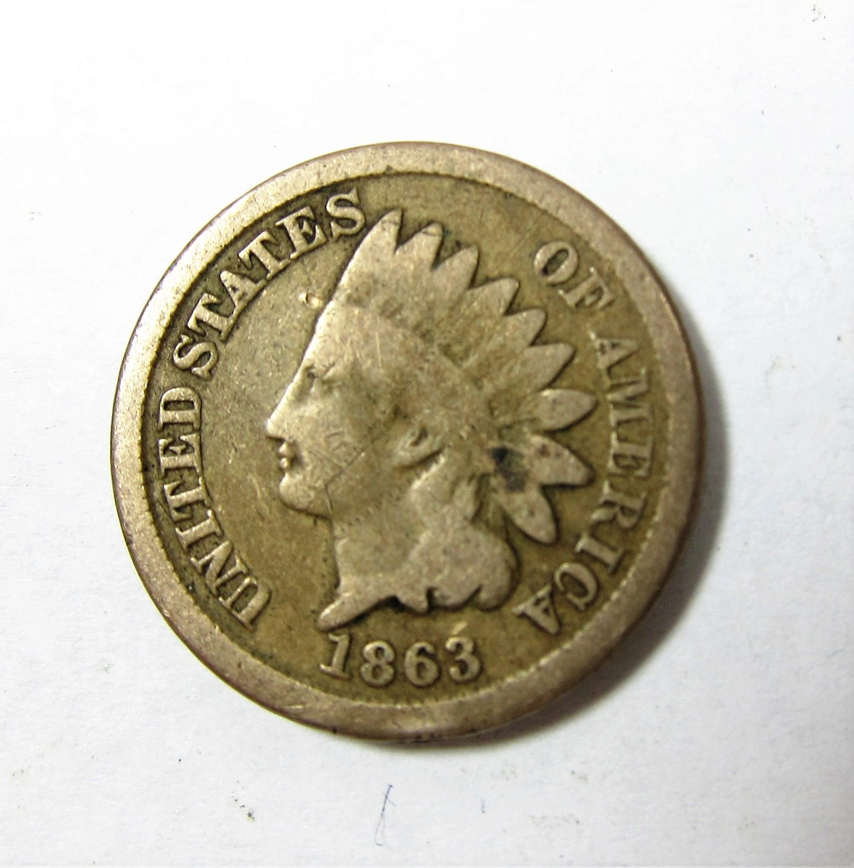 1863 Indian Head One Cent coin featuring Lady Liberty in a Native American headdress, with "UNITED STATES OF AMERICA" inscribed along the edge.