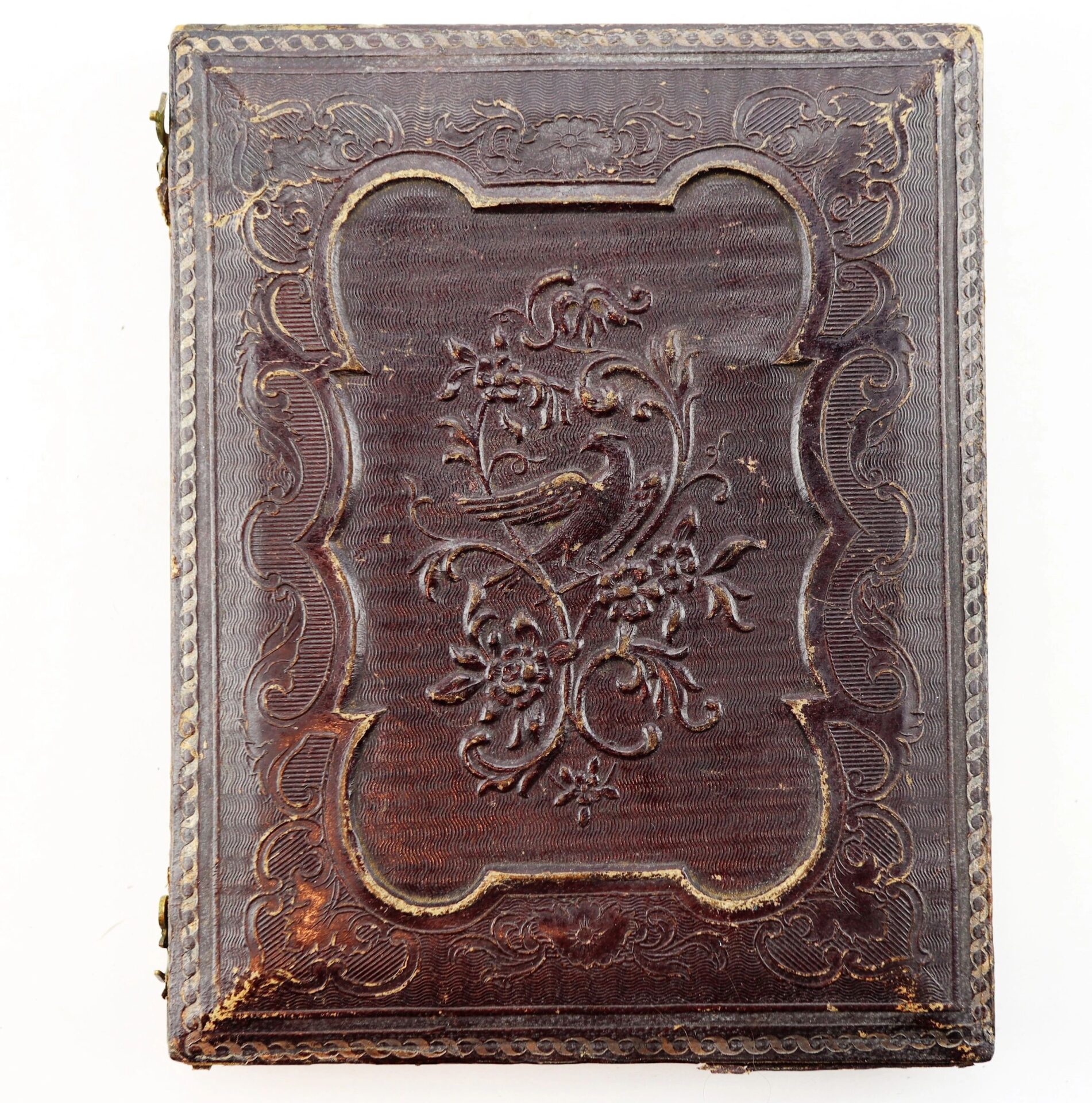 A closed, ornate brown leather Masonic Daguerreotype case with embossed floral and bird designs on the cover, showing minor edge wear.