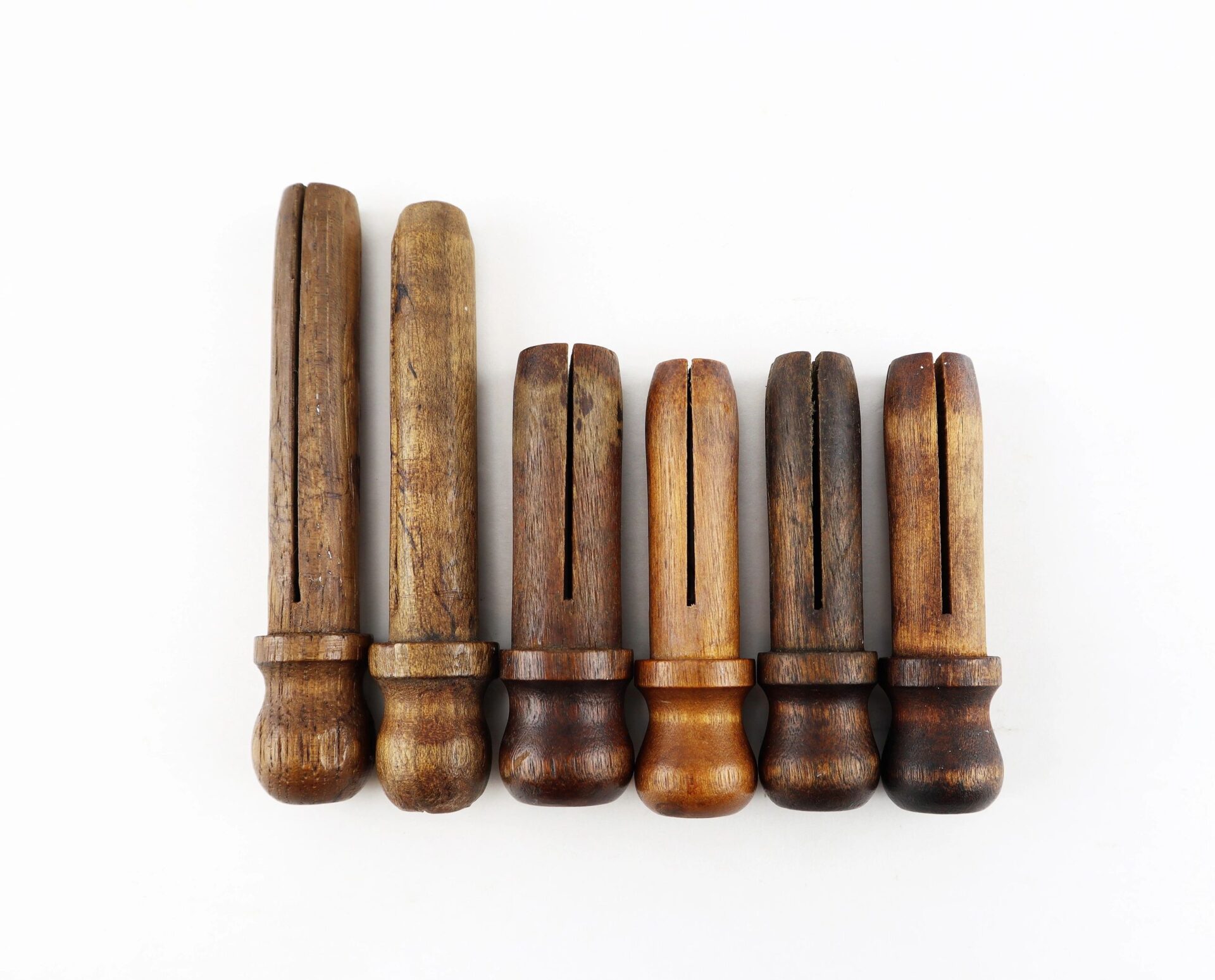 Six Civil War musket tompions, featuring grooved wooden designs, arranged in a row on a white background.