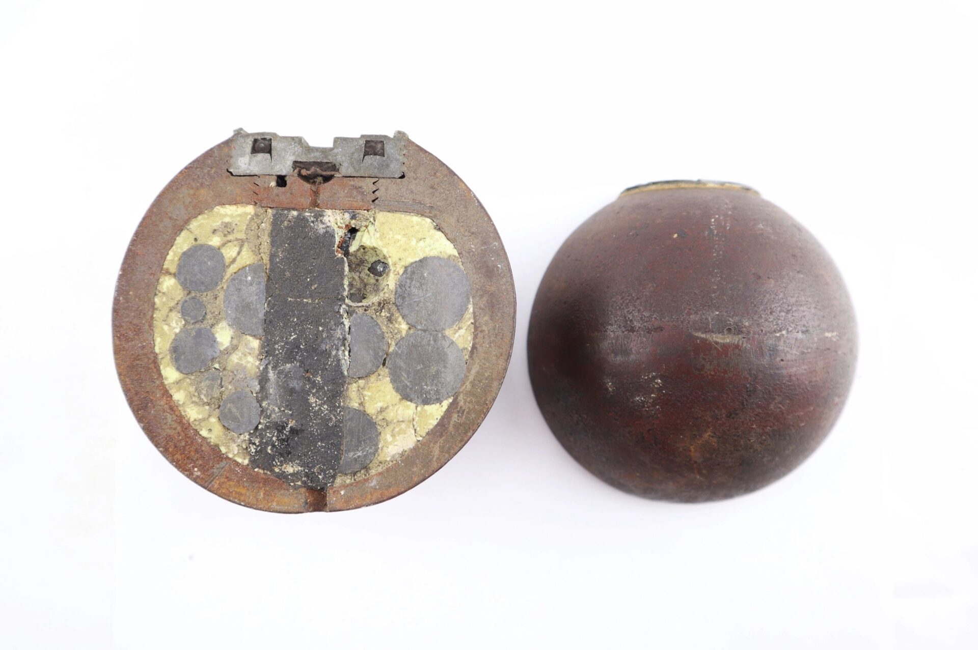 The Confederate 6 Pound Borman Artillery Shell is shown: one shell cut open to display inner circular compartments, and another intact with a smooth brown surface.
