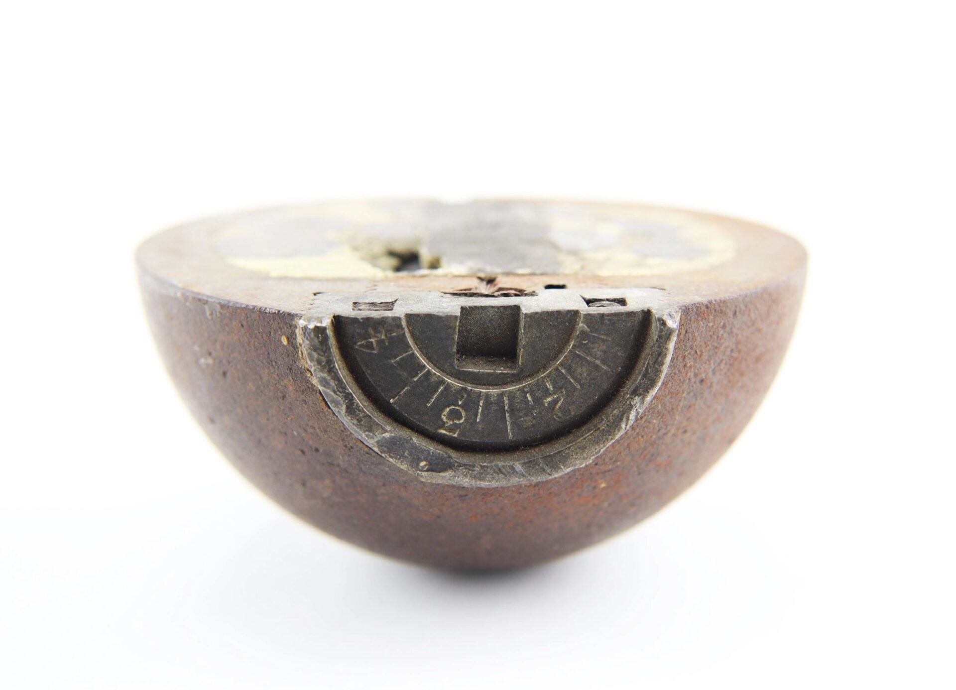 A Confederate 6 Pound Borman artillery shell, rusted and partially cut open to reveal a numbered dial with a rectangular slot on its inner surface.