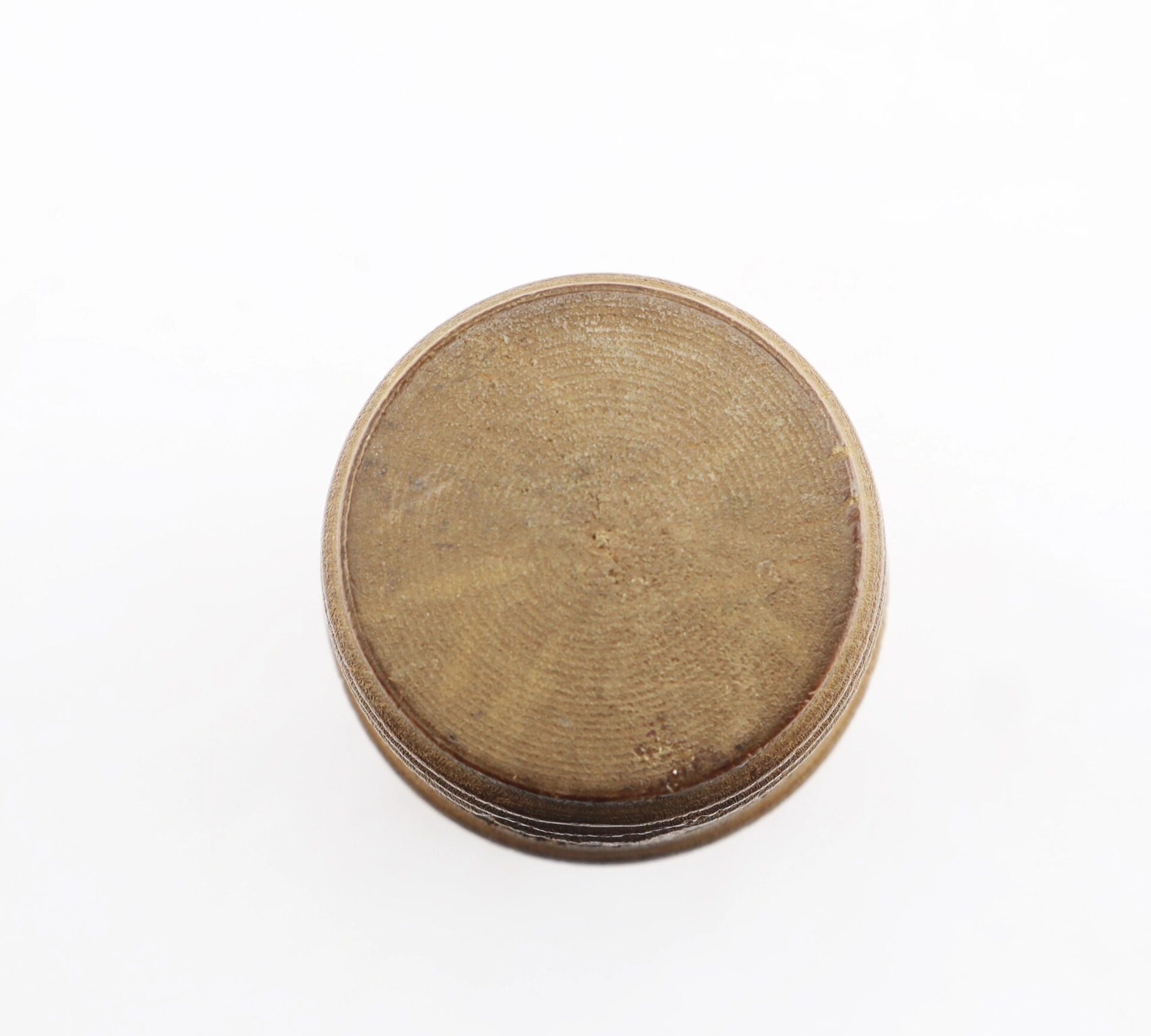 A round, flat metallic Knucklebones piece with a textured surface is shown from above against a plain white background.