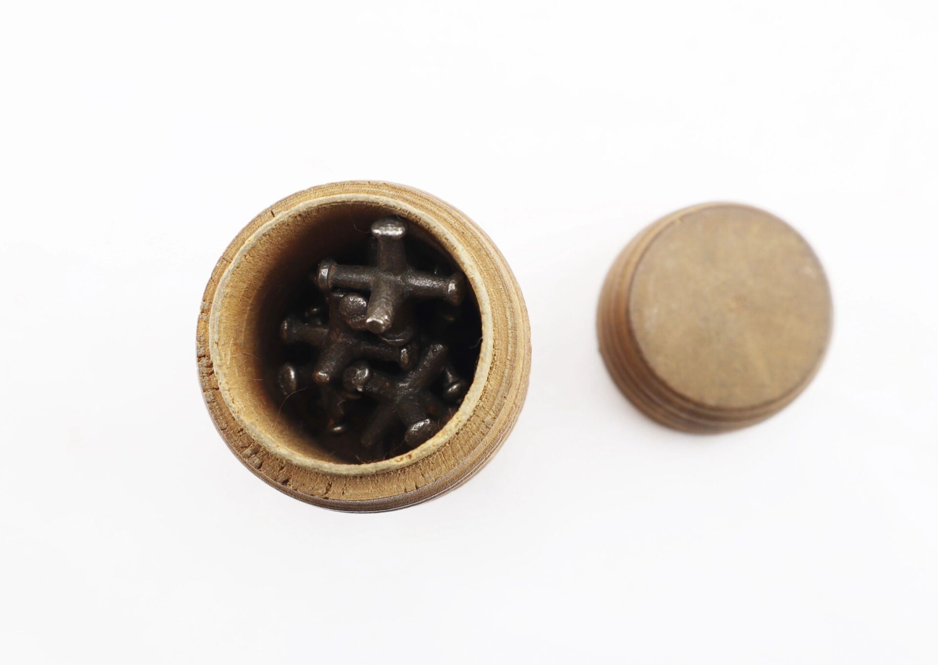 An open small wooden container filled with several knucklebones. Product Name: Knucklebones / Sold.