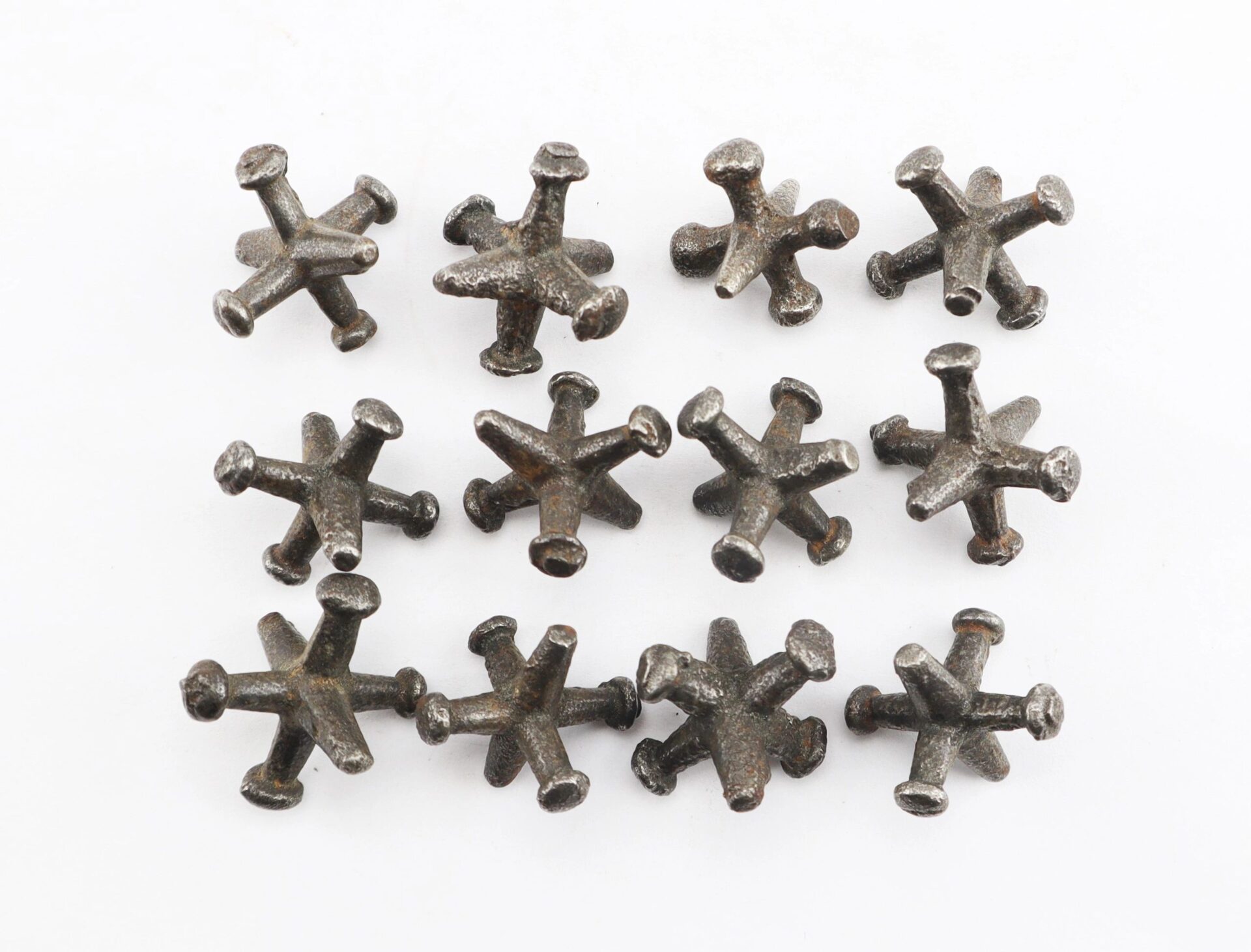 Twelve Knucklebones jacks arranged in three rows on a white background.