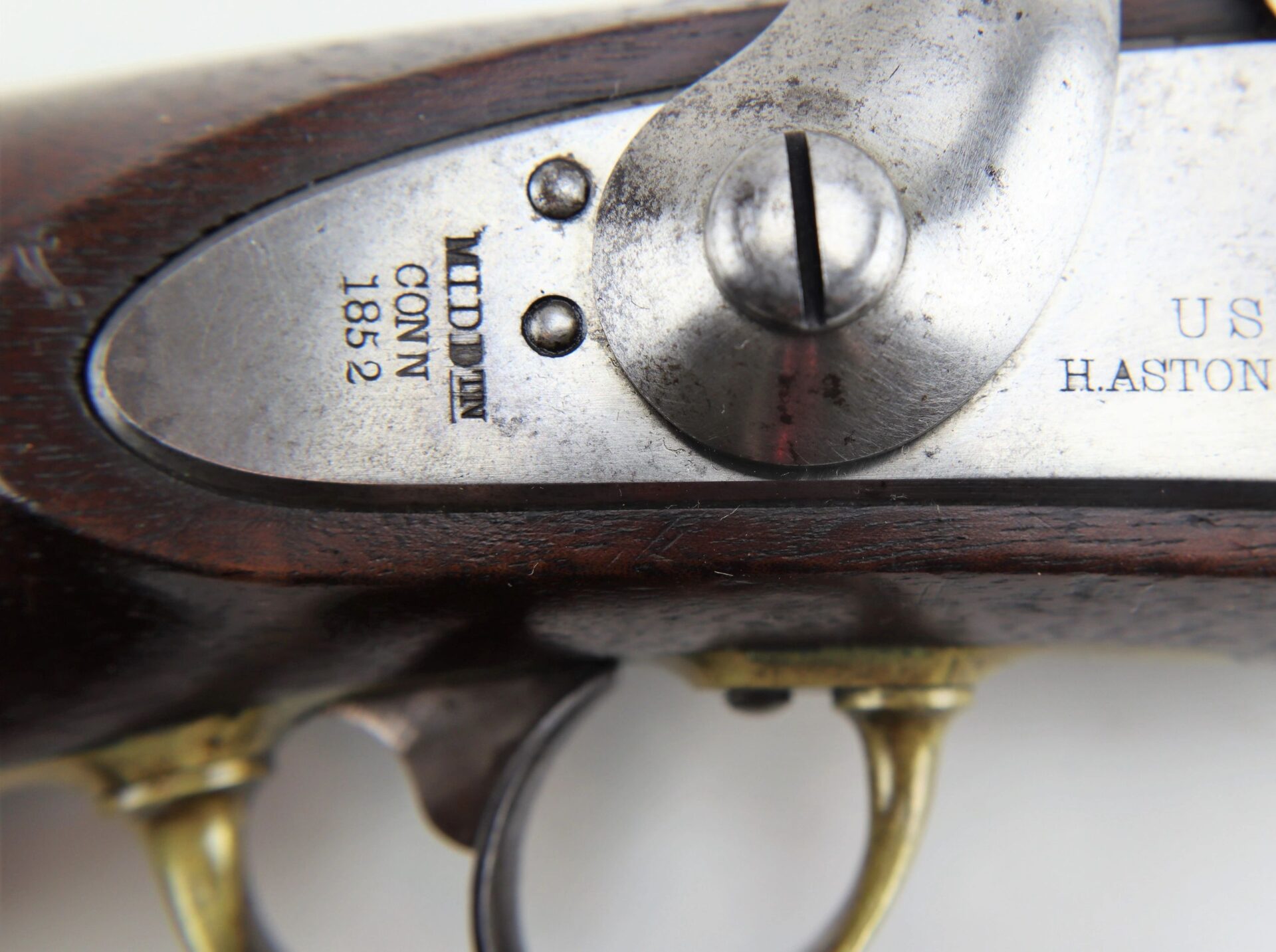 Close-up of an Aston Horse Pistol/SOLD lockplate engraved "MIDD'N CONN 1852," with part of the trigger and wooden stock visible.