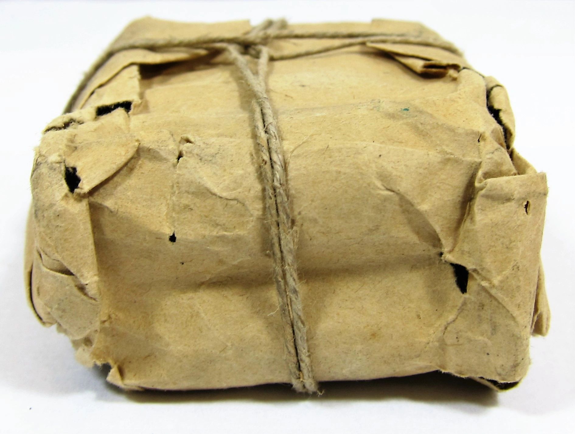 A Maynard Carbine Cartridge, wrapped in brown paper with twine and visible creases, sits against a plain background.