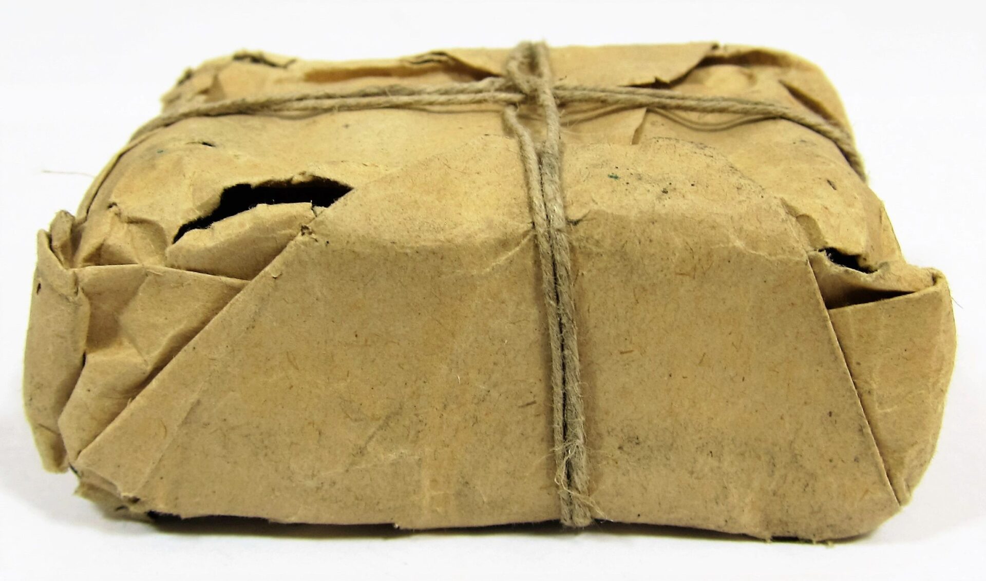 A Maynard Carbine Cartridge in a small rectangular package, wrapped in brown paper with string; the paper shows visible creases and small tears.
