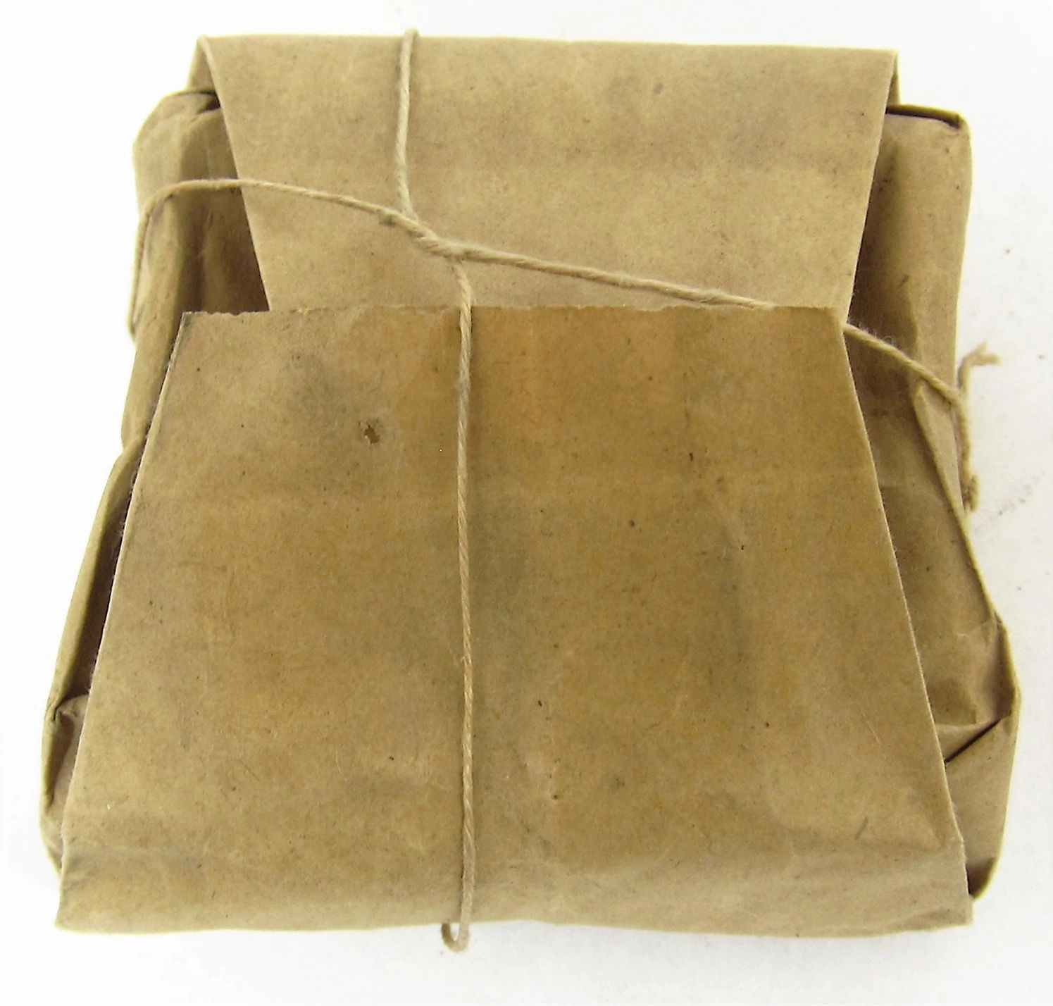 A .58 Caliber Minie Ball paper wrapper, rectangular and tied with string, rests on a plain white surface.