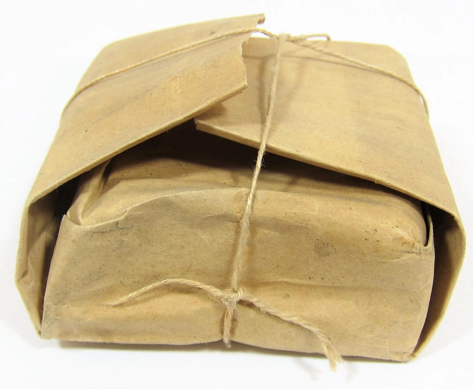 A .58 Caliber Minie Ball Paper Wrapper, partially opened at one end, tied with string and placed on a white background.
