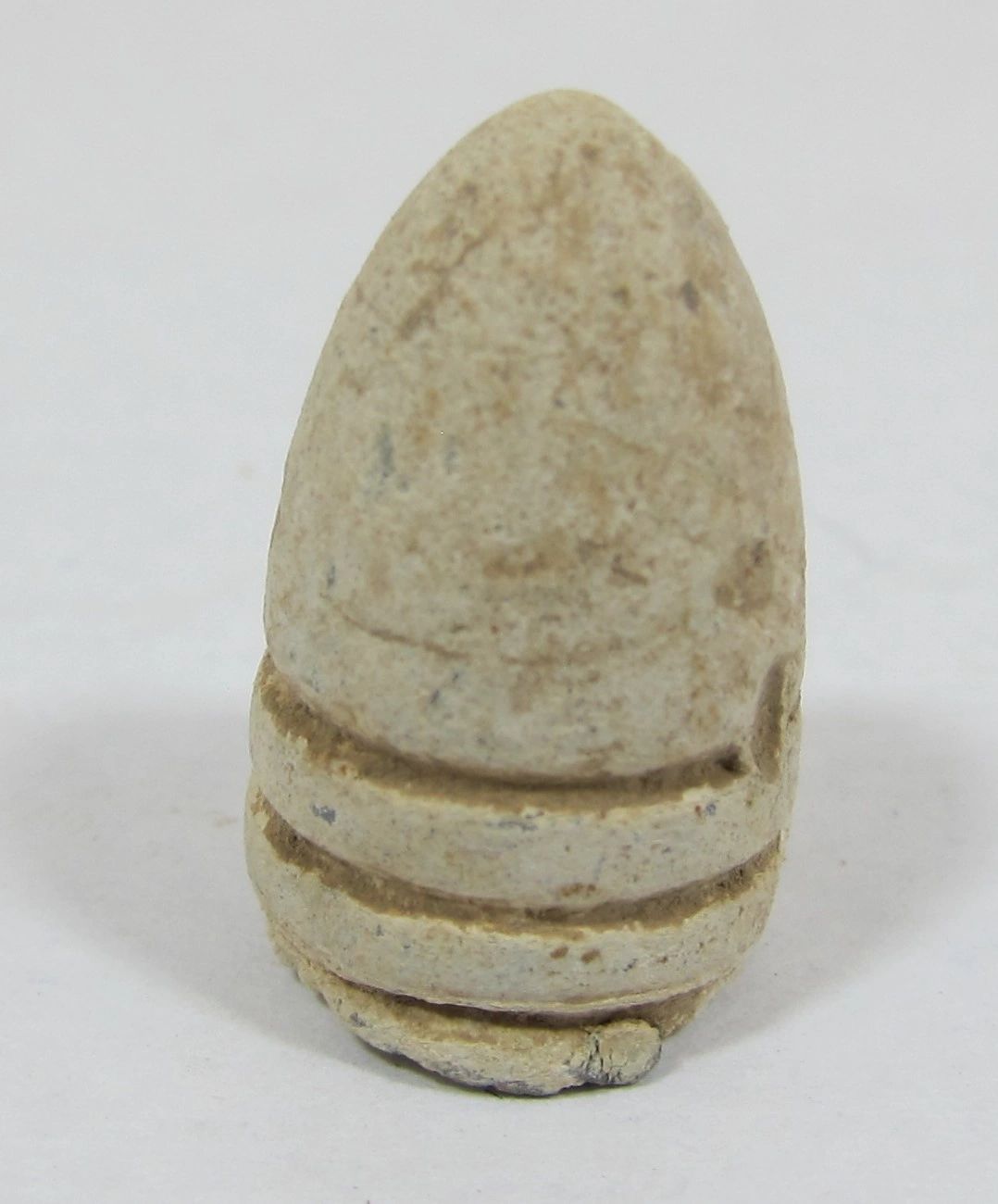 A close-up photo of a weathered, light-colored Carbine Bullet from Gettysburg with two grooves near the base, displayed against a plain white background.