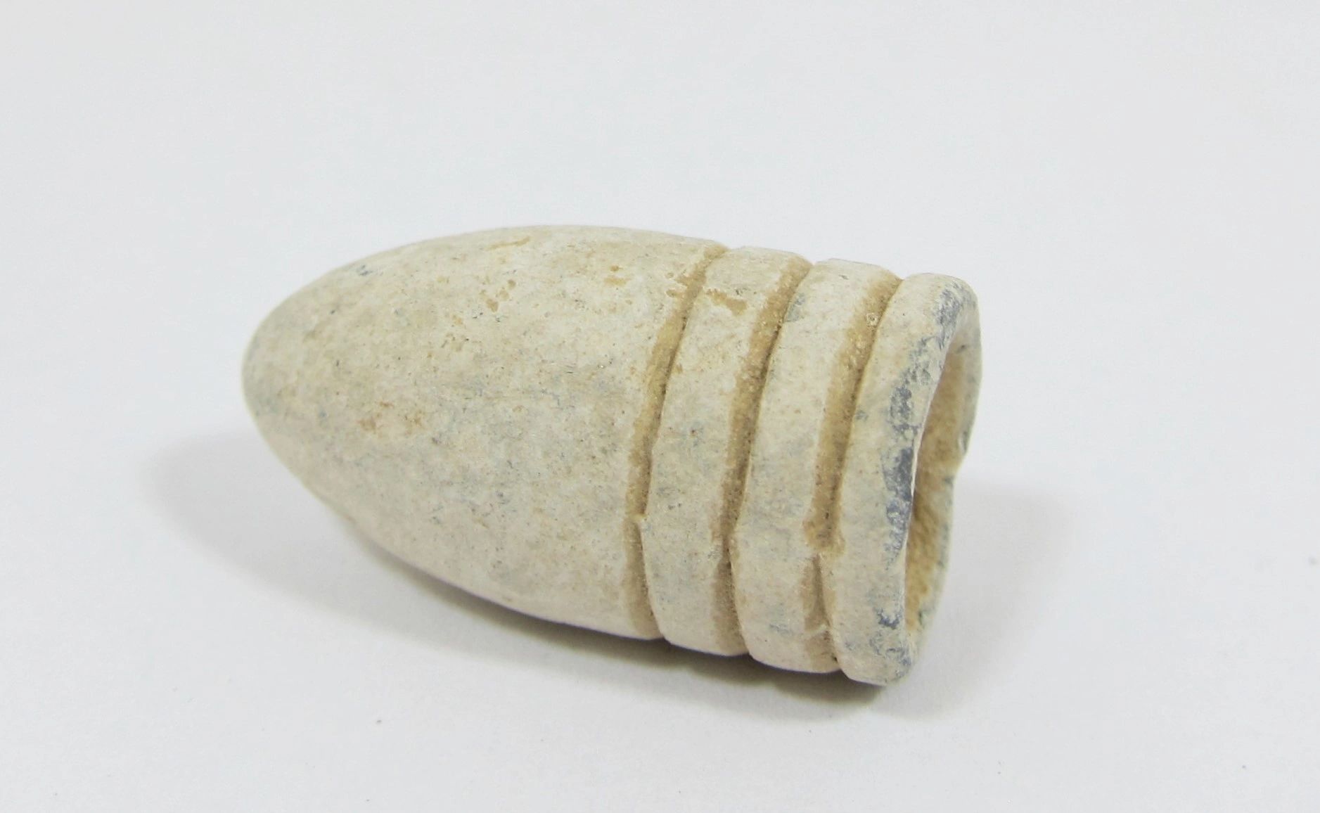 A close-up of a .58 Caliber 3-Ring Union Bullet from Gettysburg, white and cylindrical with three grooves, displayed on a plain white background.