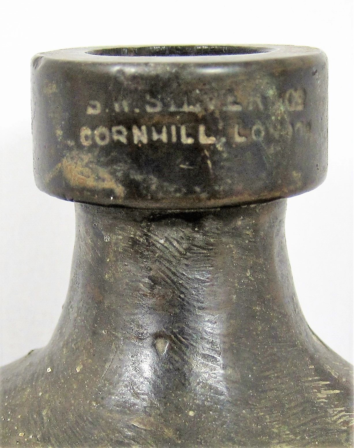 Close-up of the neck of a Civil War Era Gutta-Percha Canteen with worn text reading "CORNHILL, LONDON" on the collar.
