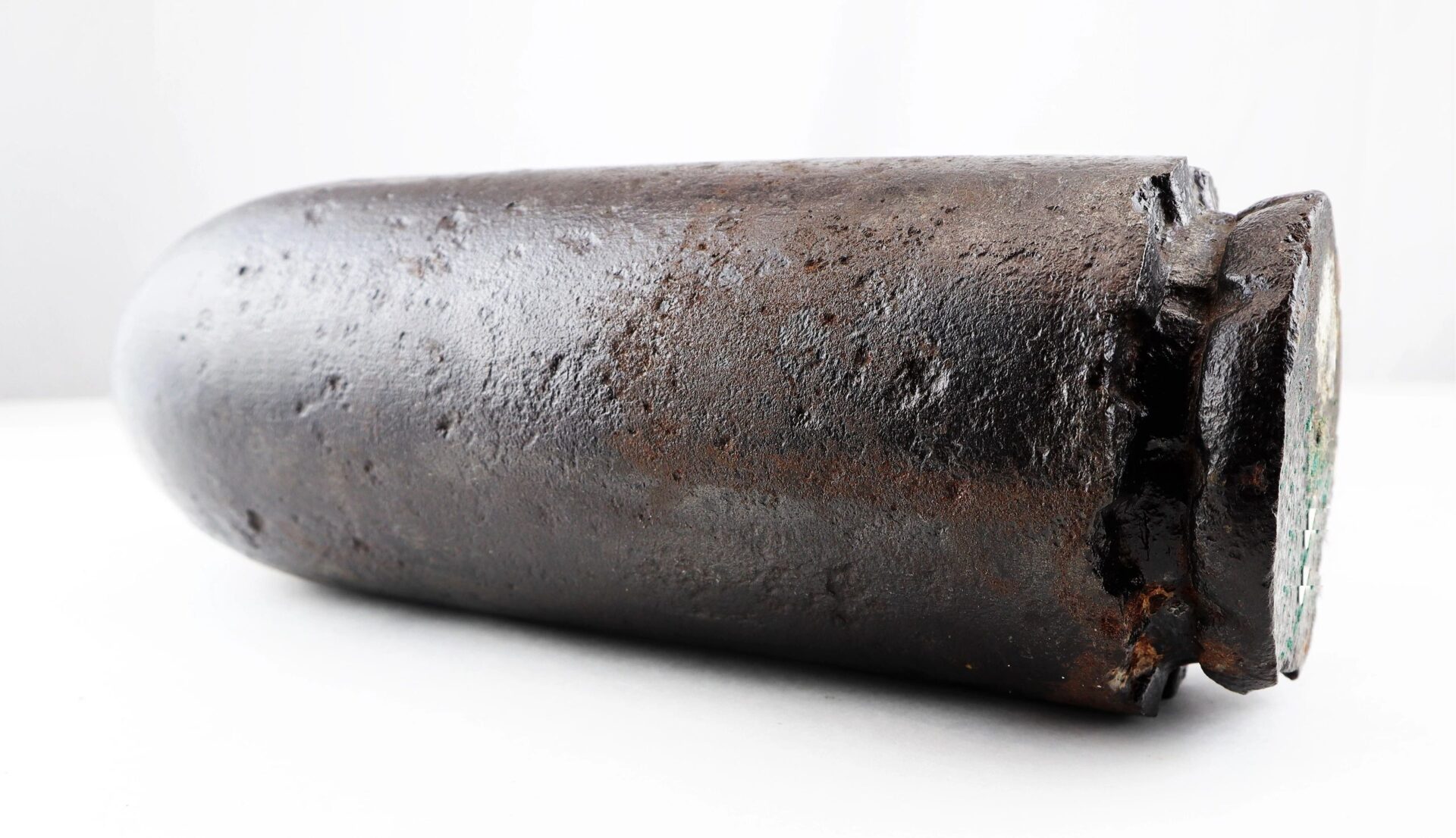 A US 4.2” 30-Pounder Parrott Common Shell, featuring rusted metal, lies on its side against a plain white background.