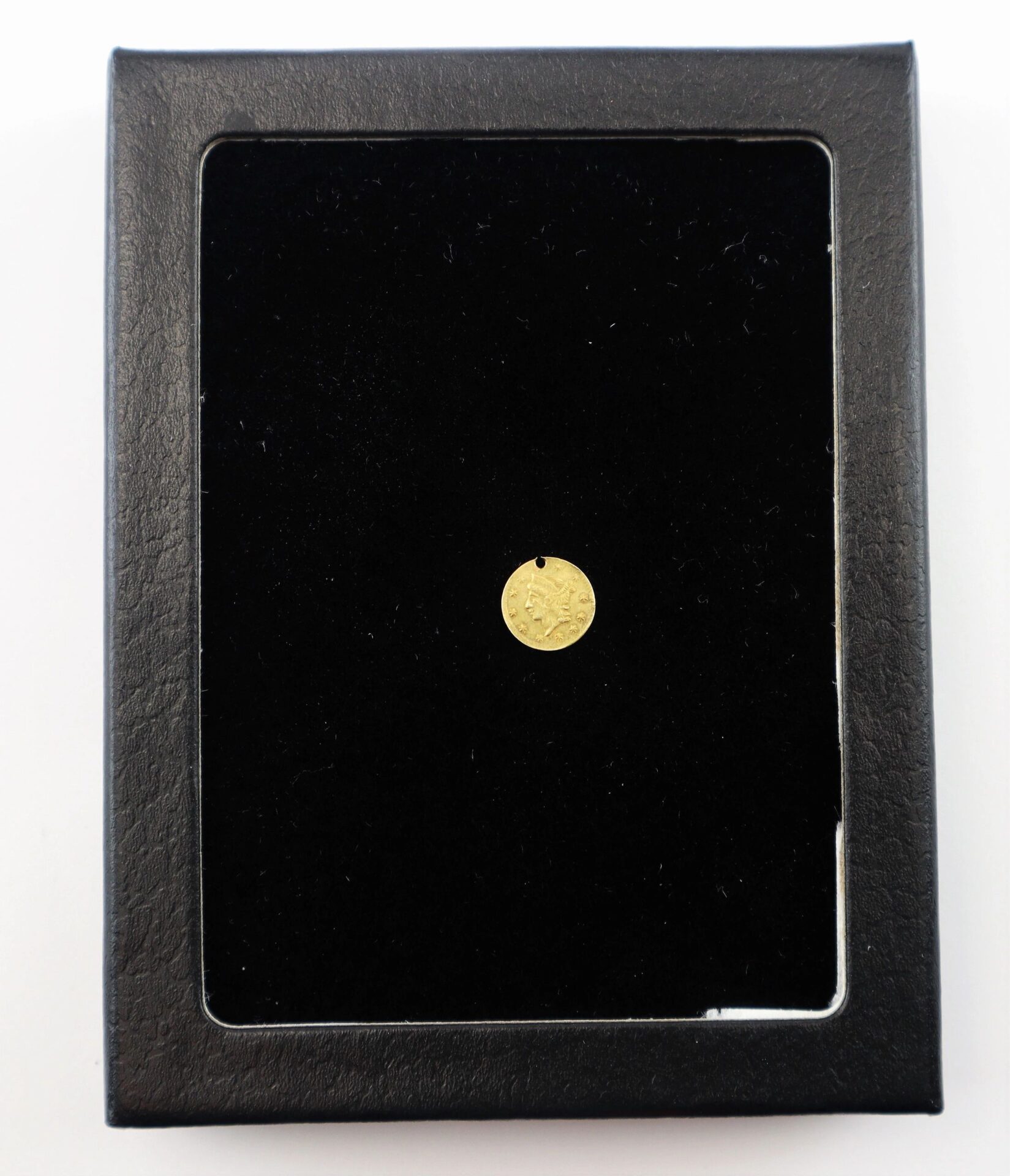 An 1860 Quarter Dollar Gold Coin / SOLD is displayed at the center of a black velvet-lined, rectangular display case, highlighting its embossed design.