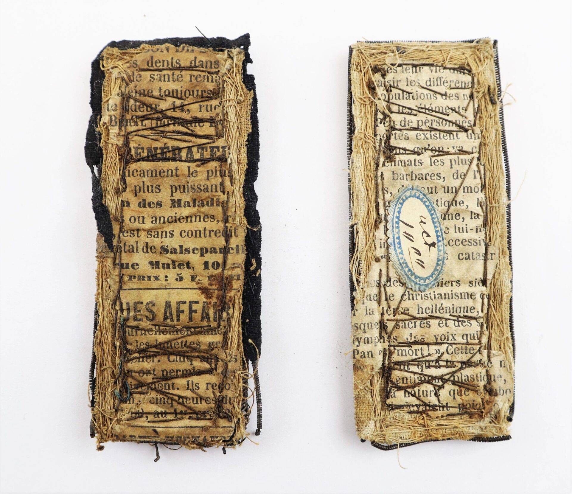 Two rectangular objects from the John Hunt Morgan Knife and Grouping ID’d to Hiram T. Fisher, 16th Ohio and 53rd USCT / SOLD, are covered with worn fabric and newspaper clippings; the right one features a small oval label with handwritten text.