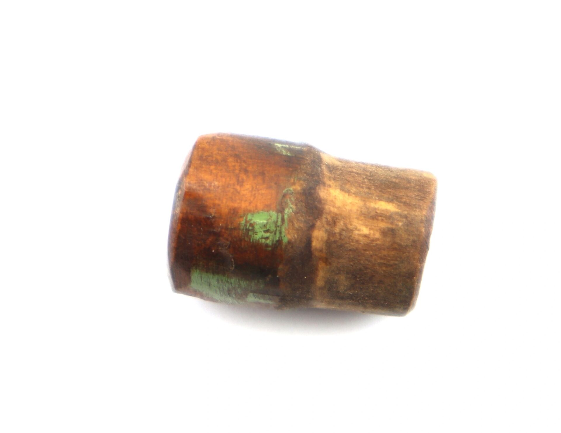 A close-up of the War of 1812 Rundlet Canteen, a small cylindrical wooden object with green paint marks, photographed on a white background.