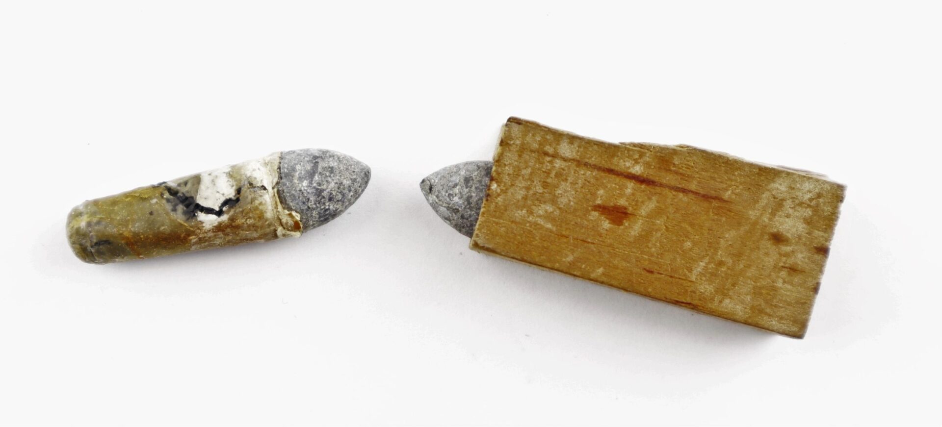 Two .36 Caliber Navy Cartridges—one partially wrapped in wood, the other with residue—are displayed on a white background.
