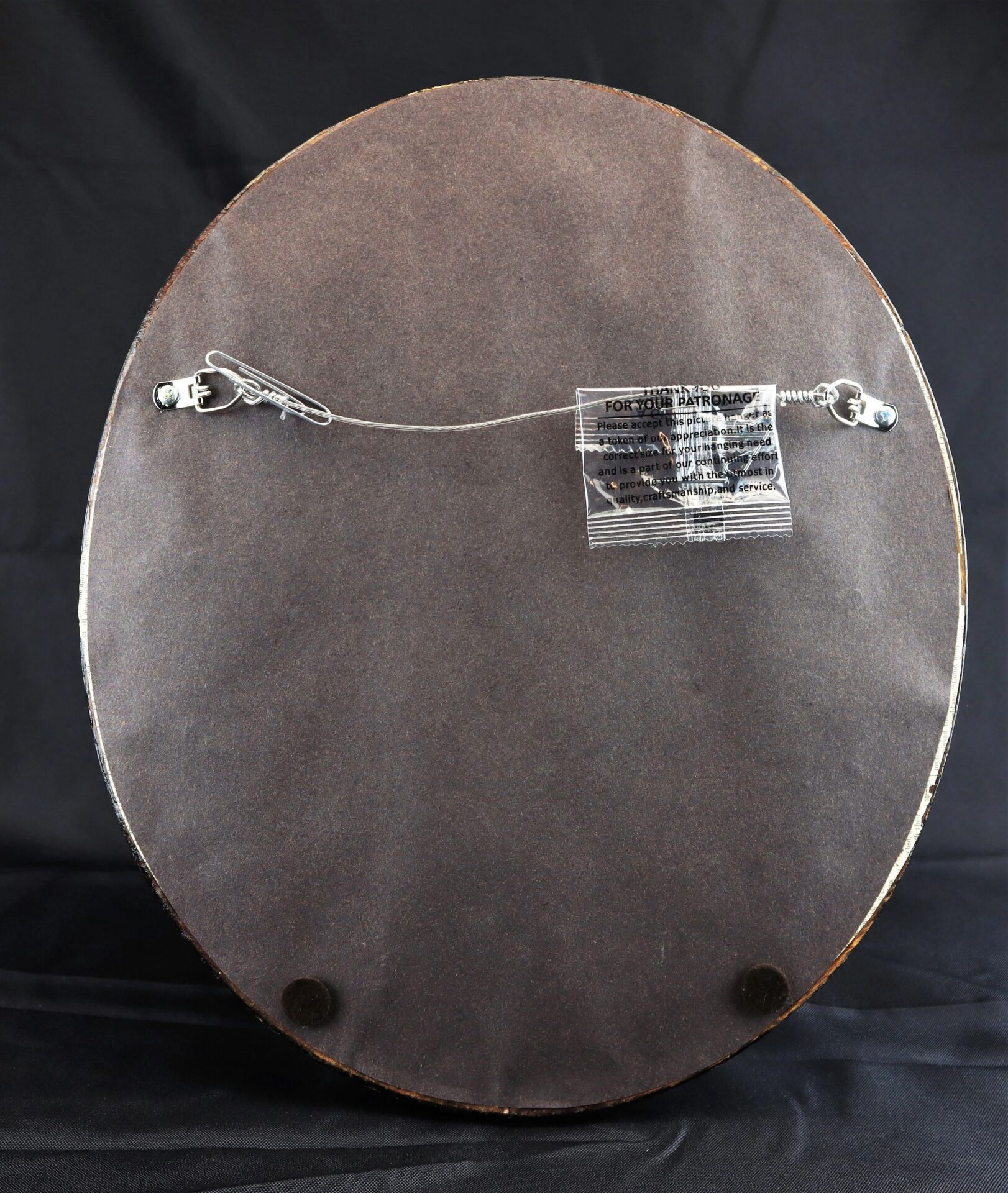 Back side of the Full Plate Ambrotype of an 1850s Militia Officer, round frame with hanging wire and two wall bumpers, set against a black background.