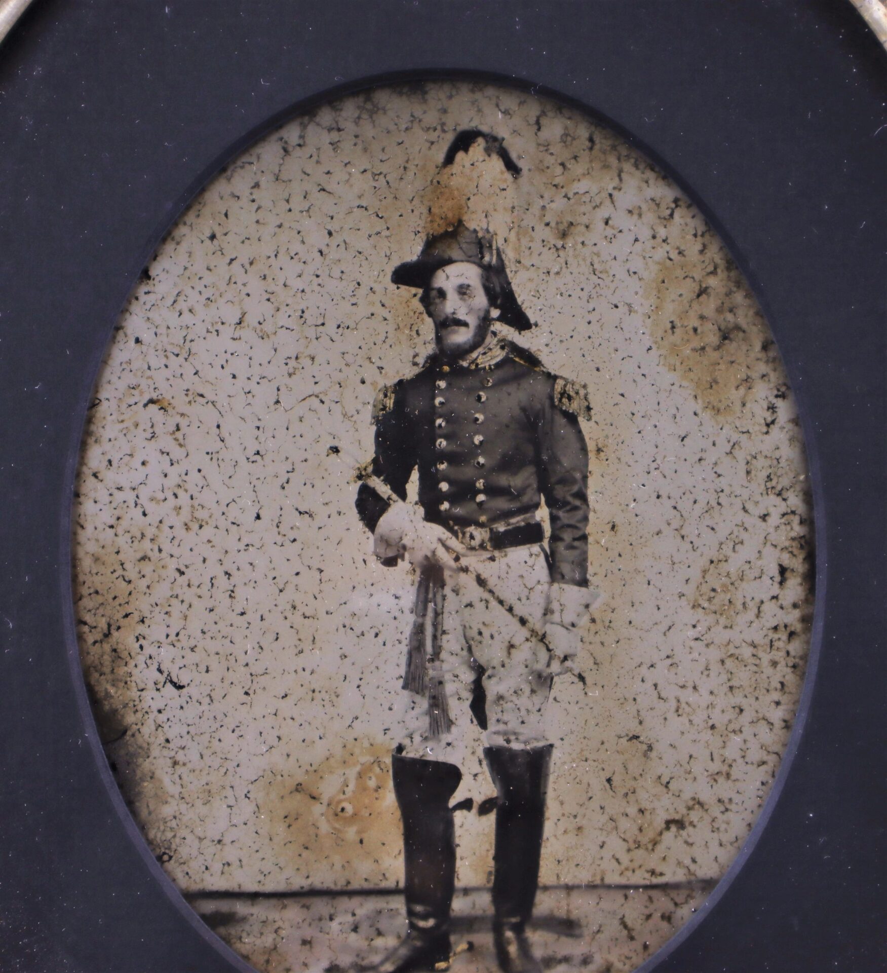 Full Plate Ambrotype of an 1850s Militia Officer: sepia image shows a man in historical military uniform with tall boots, feathered hat, and staff, posed against a plain background.