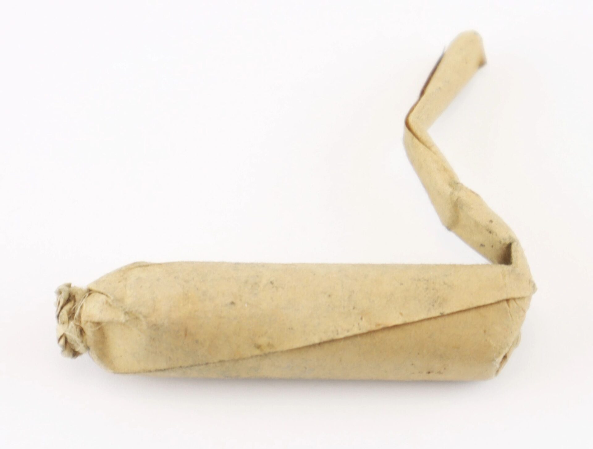 A Civil War .58 Caliber Minie Ball Cartridge, featuring a brown paper wrap with a twisted end and an unrolled strip of paper extending from one side. / SOLD.