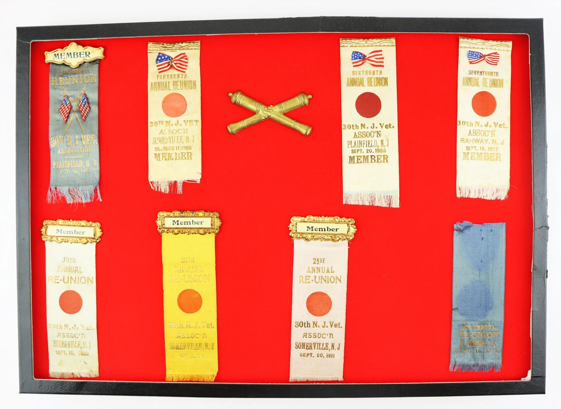 A display case featuring the Discharges, Bible, and Reunion Ribbons of David R. Weaver, 30th NJ Infantry and Battery D, 1st NJ Light Artillery—includes vintage ribbons and gold crossed cannons on a red background.