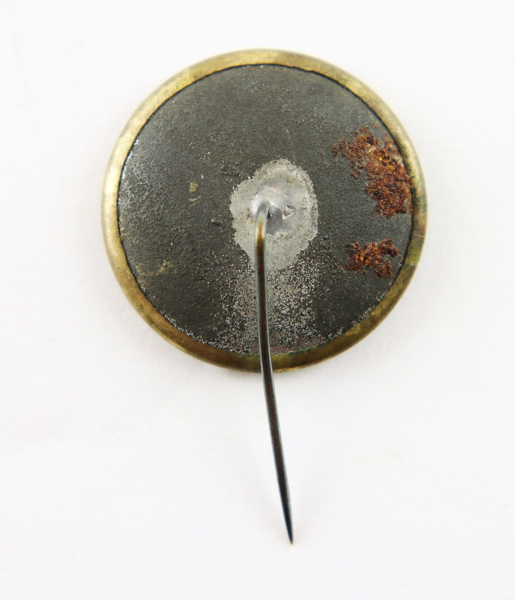 The back of a round George McClellan Ferrotype Pin, featuring metal with visible rust and a sharp pin-back.