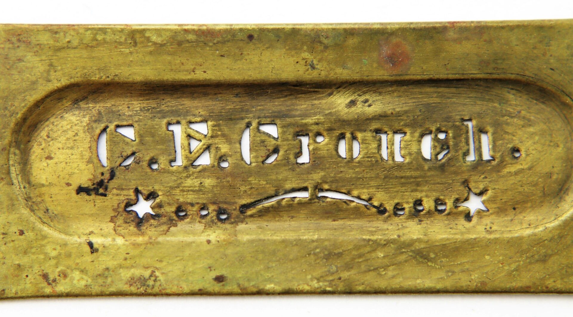 A brass identification stencil reading “Charles E. Crouch, 9th New Hampshire Infantry” with decorative stars and dots beneath the name.