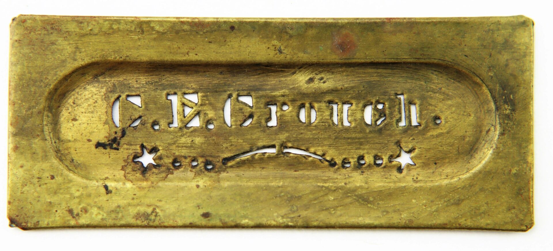 A brass identification stencil for Charles E. Crouch, 9th New Hampshire Infantry, featuring his name cut out with decorative dots and stars below.