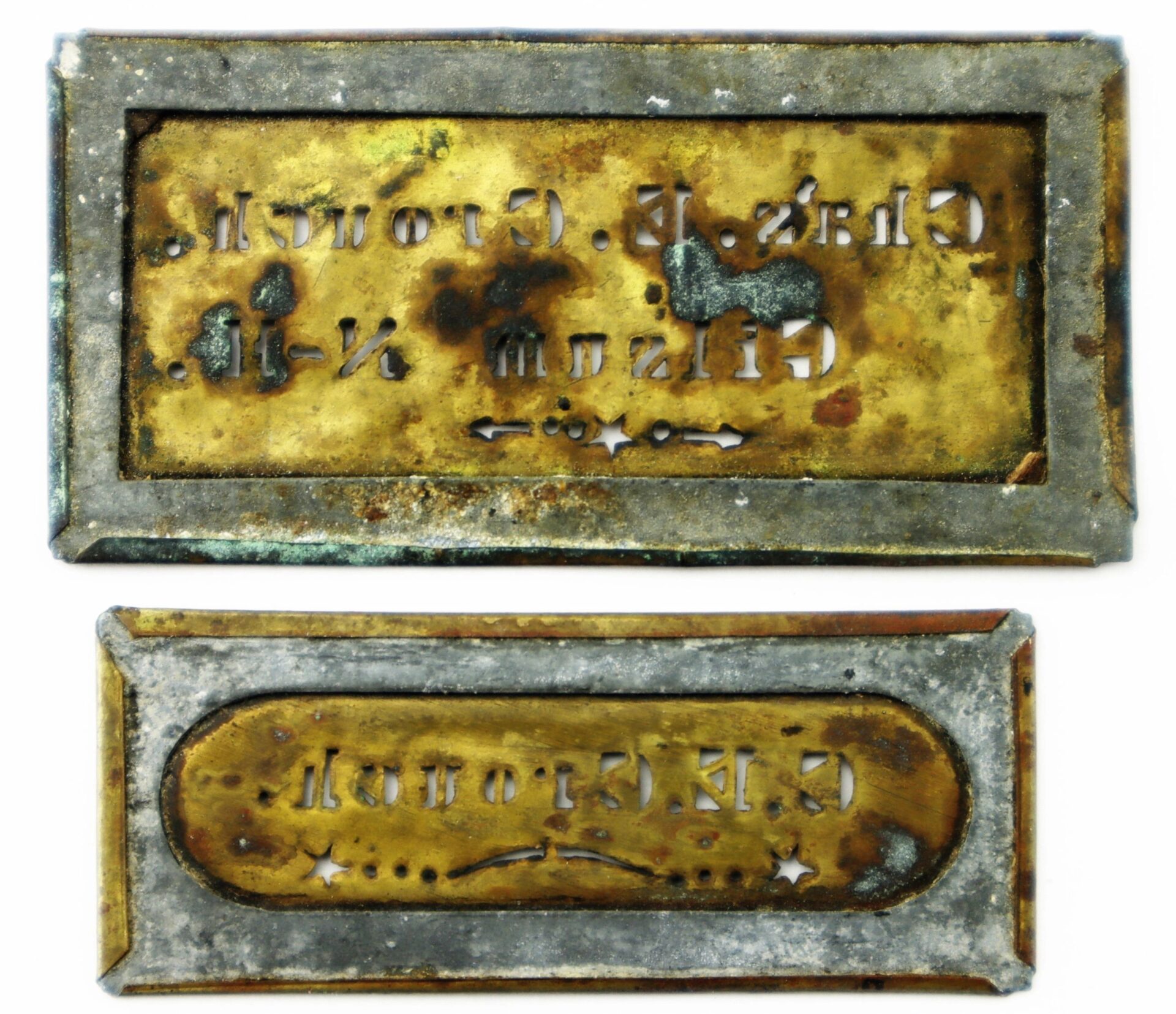 Two rectangular, corroded metal nameplates—Identification Stencils of Charles E. Crouch, 9th New Hampshire Infantry—with backward, partially legible engravings displayed side by side on a white background.