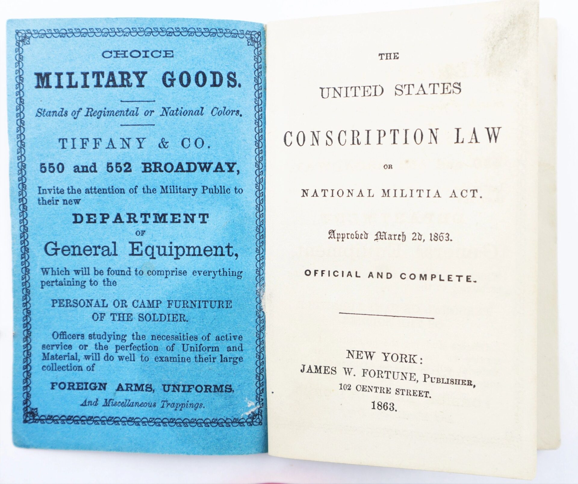 Open booklet displaying a military goods ad on the left and the title page of "The United States Conscription Law of 1863 Official and Complete, Enabled Colored Men to Enlist in the War Effort!" on the right.
