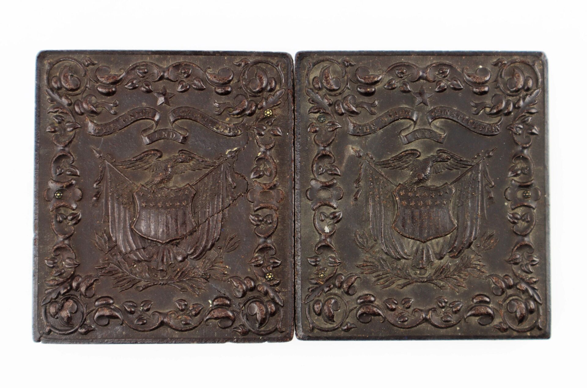 Two ornate, square, dark-colored cases with embossed eagle, shield, and banner designs contain a 1/6th Plate Tintype of a Union Infantry Corporal with Enfield Rifle Musket. The cases are placed side by side on a white background.
