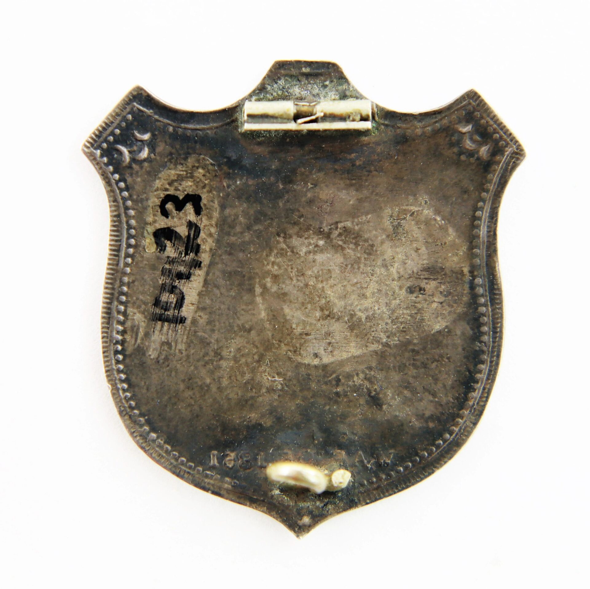 Back view of the Shield Identification Badge of Private William Harlow Marshall, 18th Massachusetts Infantry, Gettysburg Veteran; tarnished metal with hinge at top, pin at bottom, and "B13" marked on left side.