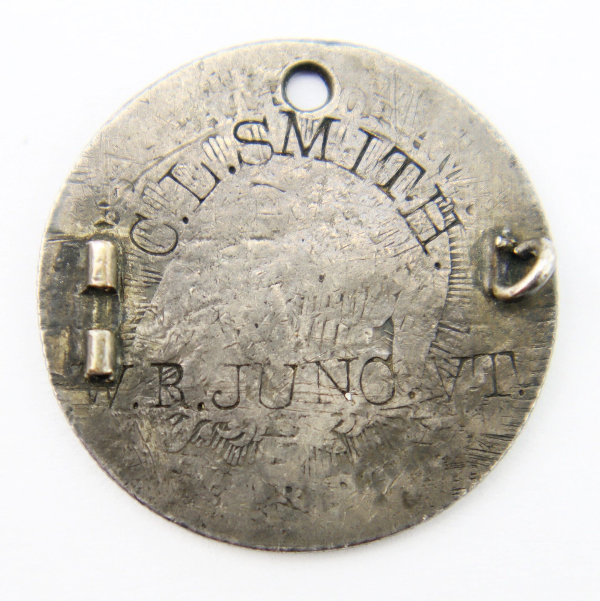 A round metal Love Token Identification Disk for Charles L. Smith, 3rd Vermont Infantry, wounded at Spotsylvania and linked to the famous “Sleeping Sentinel” Abraham Lincoln pardon; it features a hole and small loop attachments.