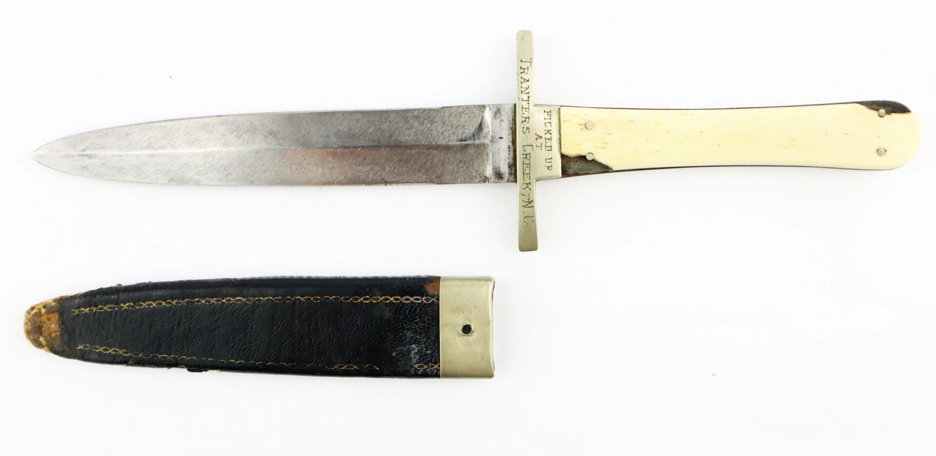 The Sheffield Dagger, picked up at Tranter’s Creek, NC by Sgt. George A. Colton, 3rd NY Cavalry/SOD, features an ivory-colored handle and brass guard, and is displayed above a black leather sheath with gold trim.