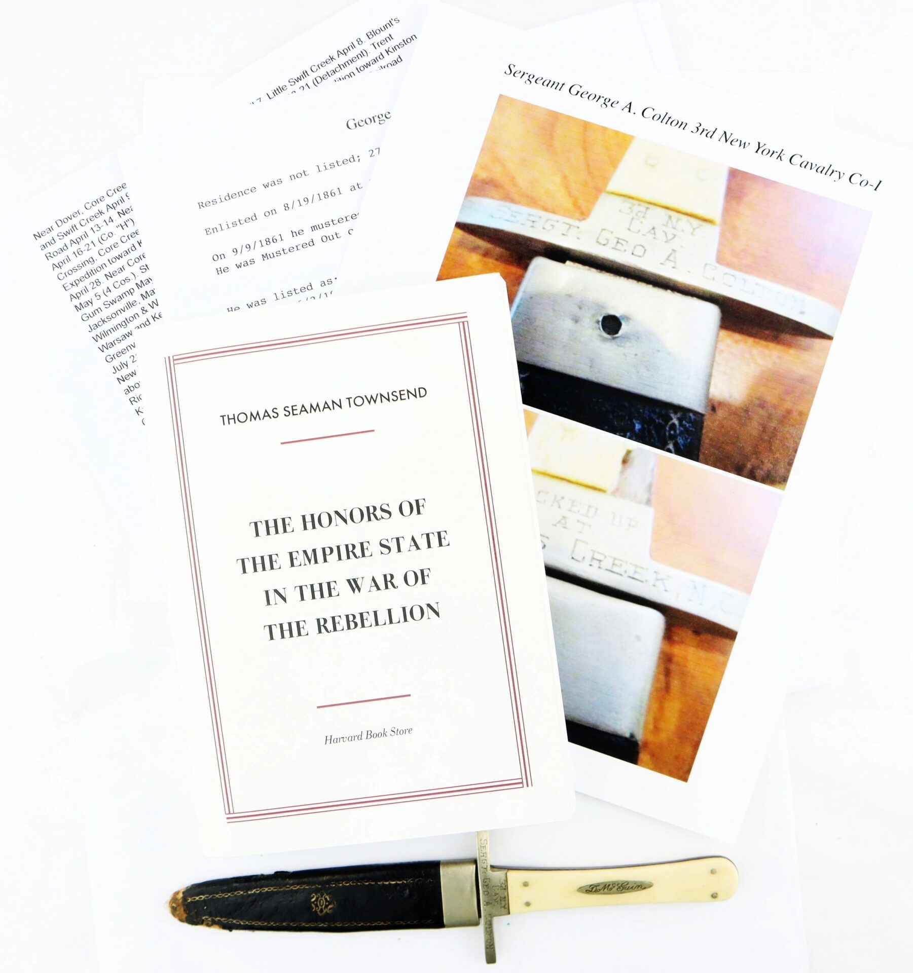 A book titled "The Honors of the Empire State in the War of the Rebellion," a Sheffield dagger found at Tranter's Creek by Sgt. George A. Colton, printed papers, and a labeled photo are displayed on a white background.