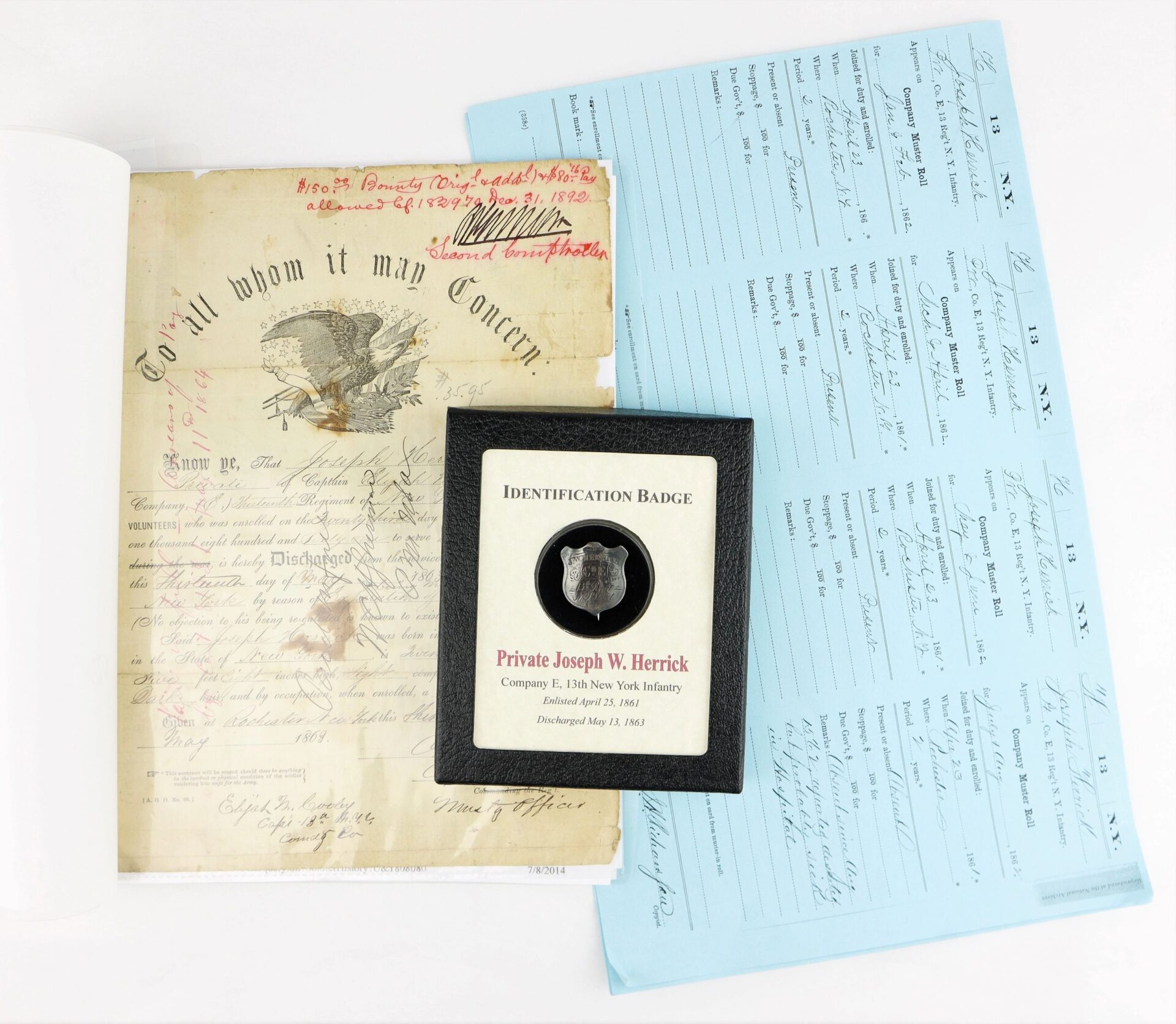 The Identification Badge and Discharge of Private Joseph W. Herrick, 13th New York Infantry, along with blue record sheets, are displayed on a white surface.