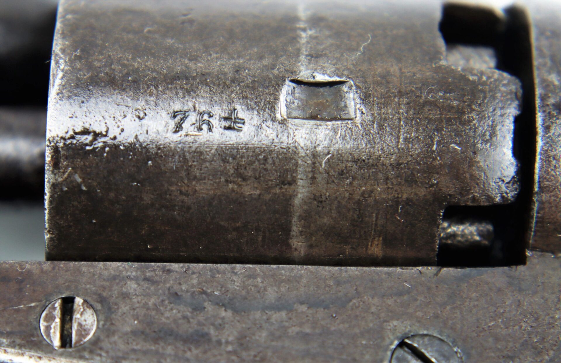 Close-up of a J. M. Cooper Pocket Model Revolver showing a metallic surface with engraved "78" and visible wear and scratches.